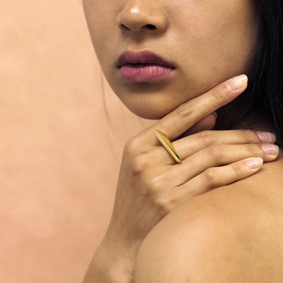 Fashion photography of a modern and unisex gold ring worn by a woman. The yellow gold architectural ring is a creation from Canadian high end jewelry brand Bena Jewelry.