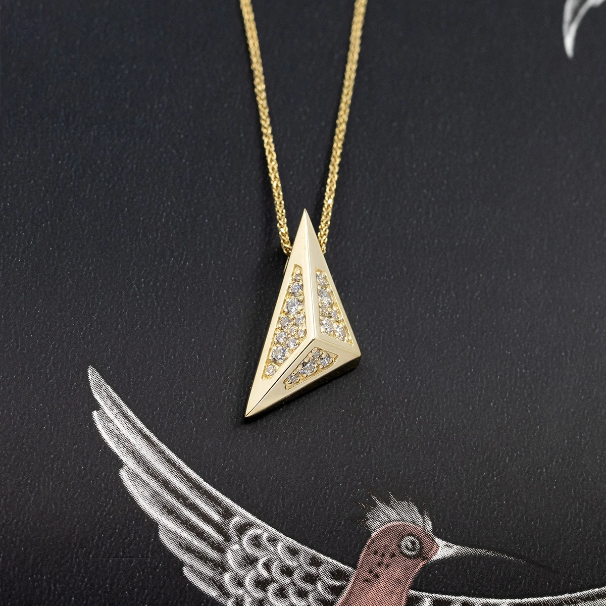Close-up of the Edgy Pyramidal Pendant in yellow gold, featuring intricate diamond paving and bold triangular lines, set against a sleek black backdrop by Bena Jewelry.