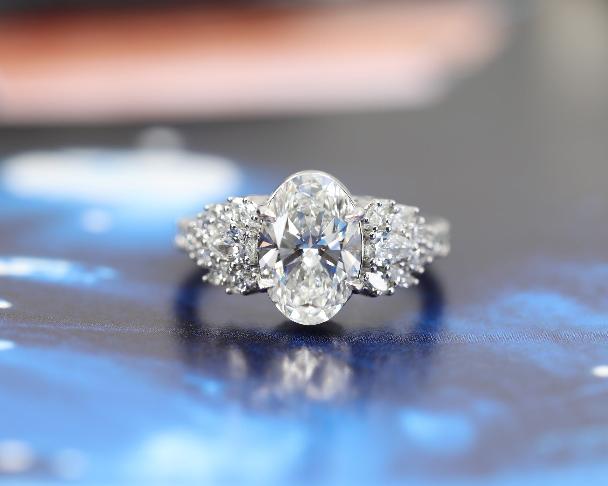 front view of oval shape lab grown diamond oval shape and side gemstone marquise and pear shape natural gems made with platinum bridal jewels on blue dark background