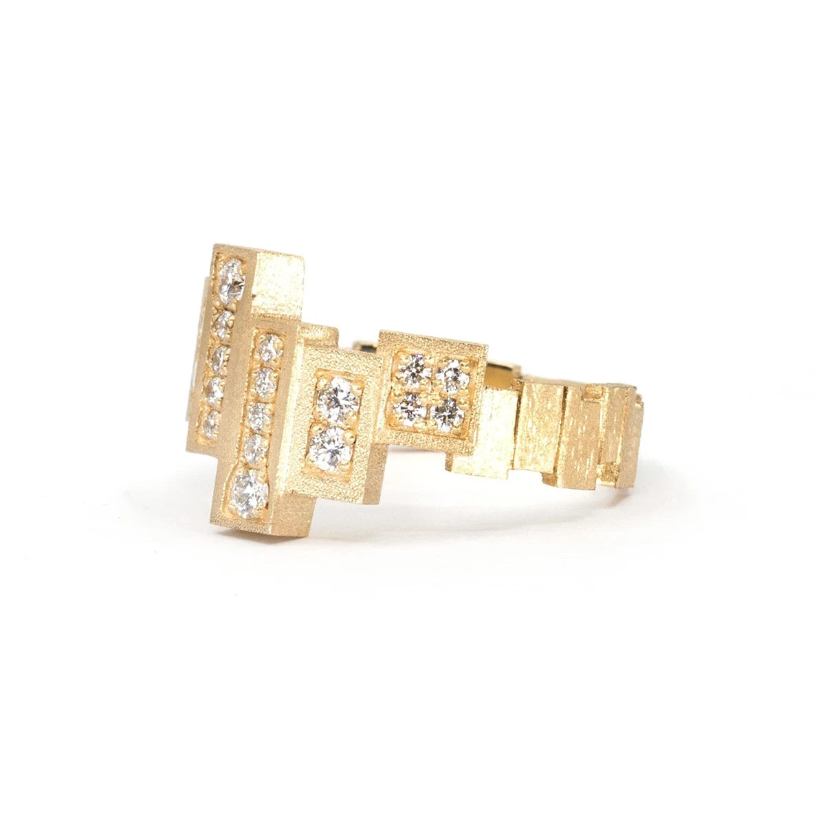 Side view of a unique, highly original ring in yellow gold with a rough finish made of several gold rectangles assembled side by side in a staggered fashion. Several of these blocks are set with extra-brilliant diamonds. The result is a jewel with a futuristic, geometric look. This fine piece of jewelry was designed and created in Montreal, Canada, by independent brand Bena Jewelry. 