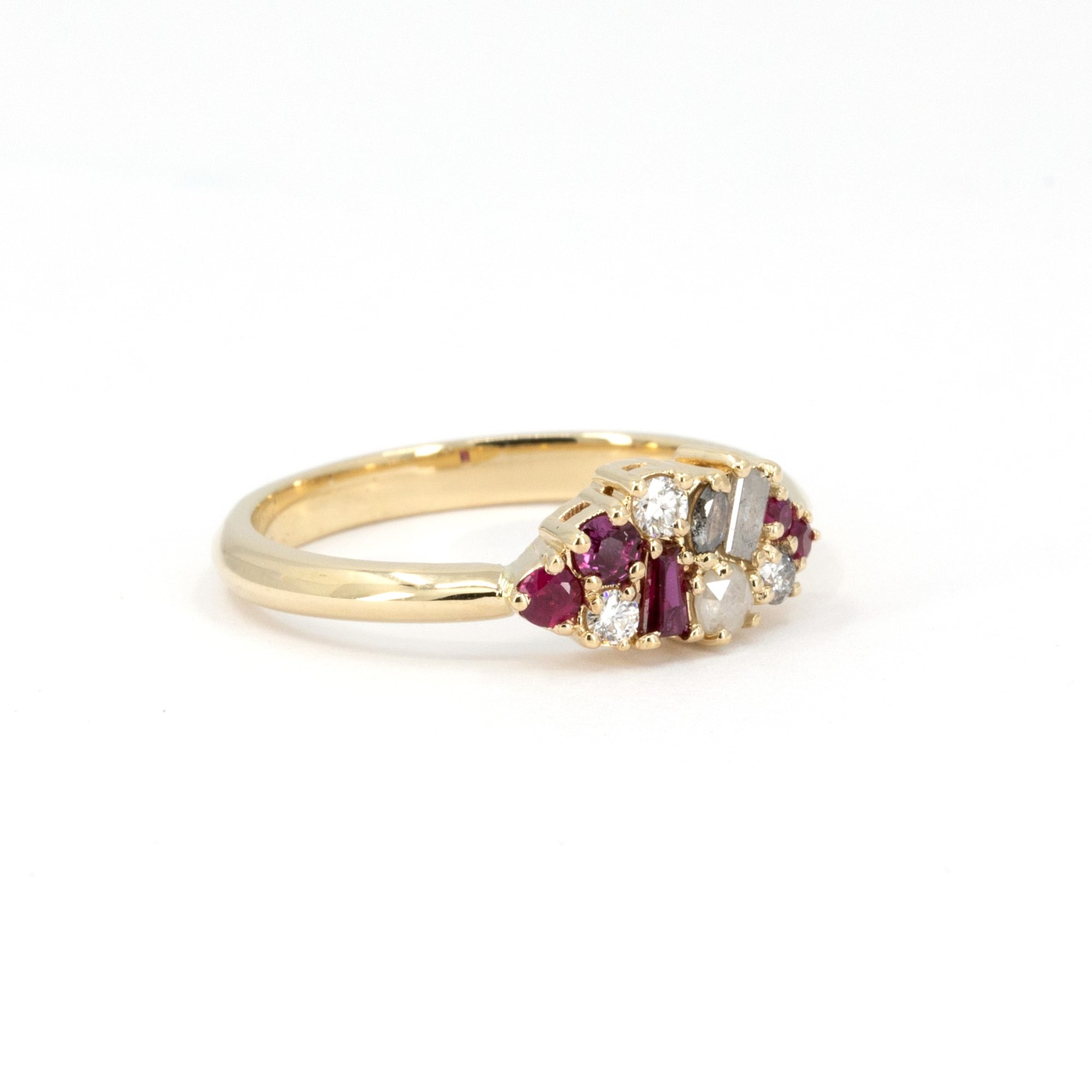 Close-up of Ruby & Salt And Pepper Diamond Avalanche Ring with unique design of rubies and diamonds set in yellow gold, photographed on a white background.