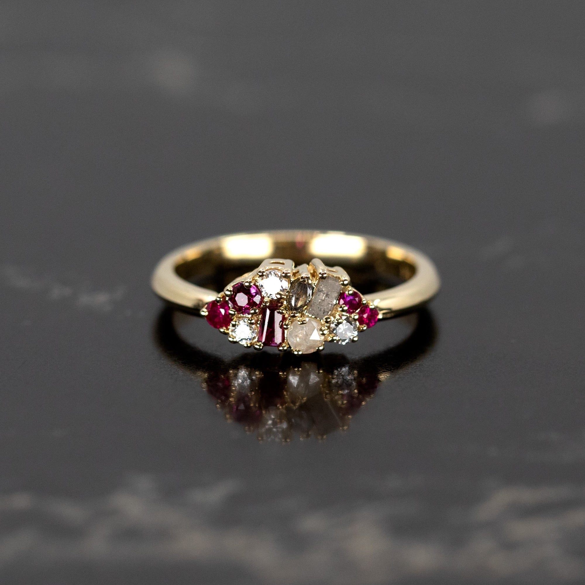 Elegant Ruby & Salt And Pepper Diamond Avalanche Ring on a dark background, featuring a unique arrangement of rubies and diamonds in yellow gold.