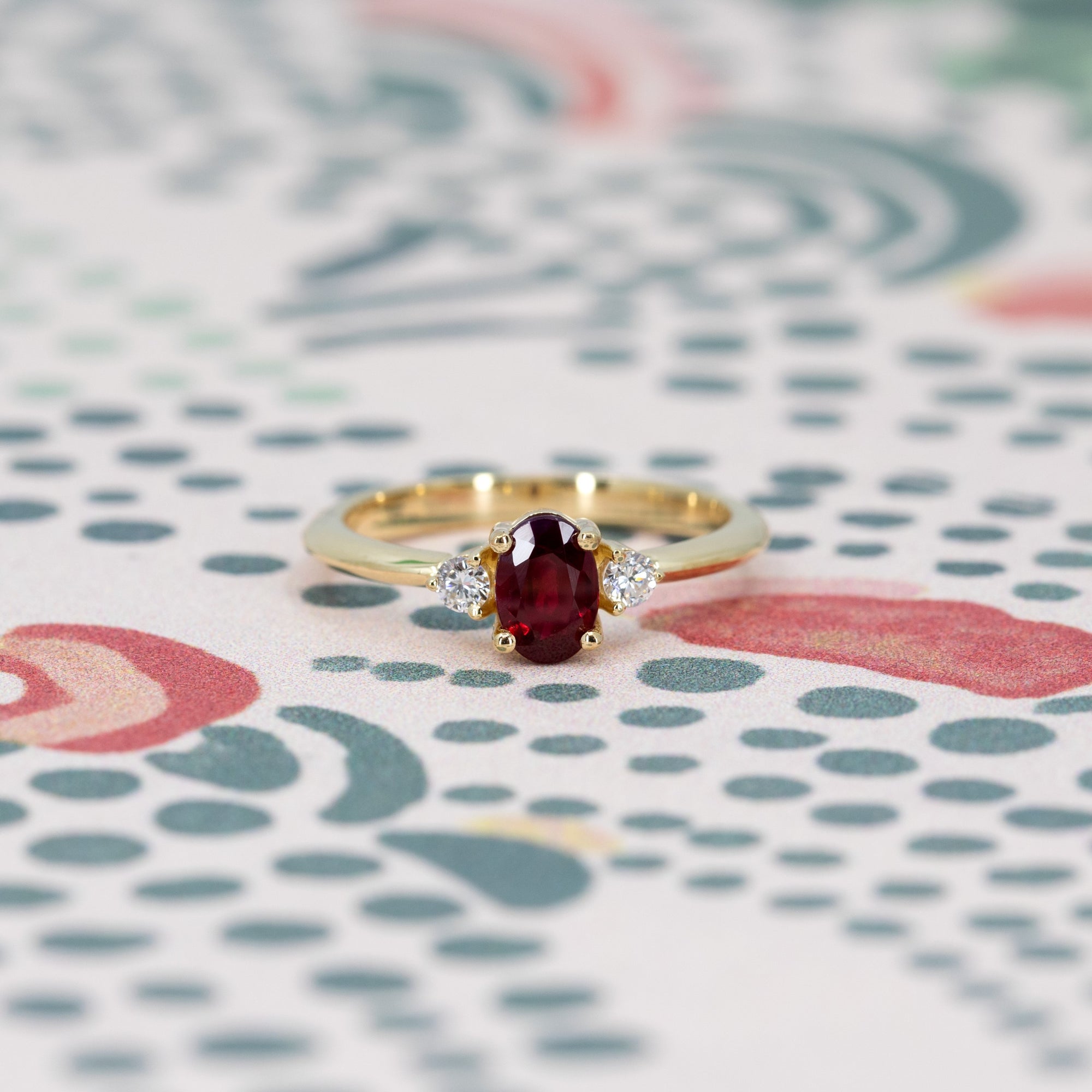 Close-up of engagement ring on dark background – The vibrant ruby and diamonds contrast beautifully with the dark setting.
