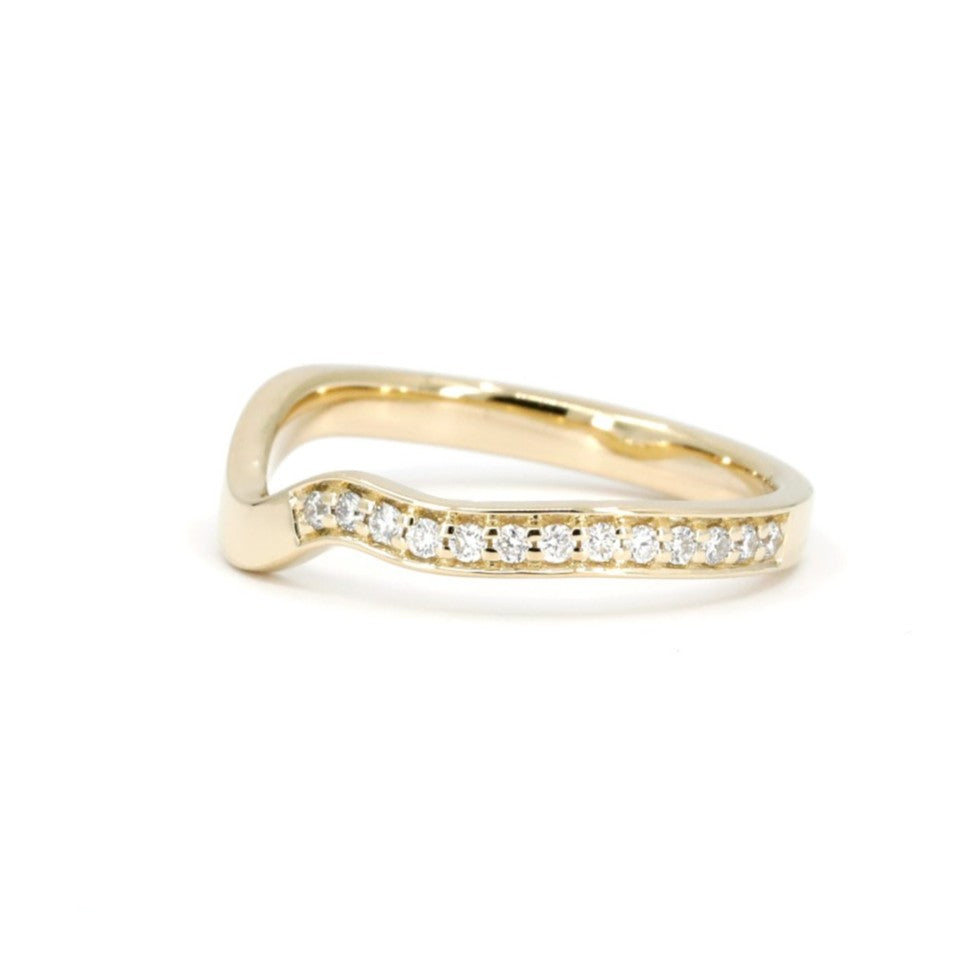 Curved yellow gold wedding band with pavé-set white diamonds, photographed on a clean white background. Designed by Bena Jewelry, made in Montreal, Canada.