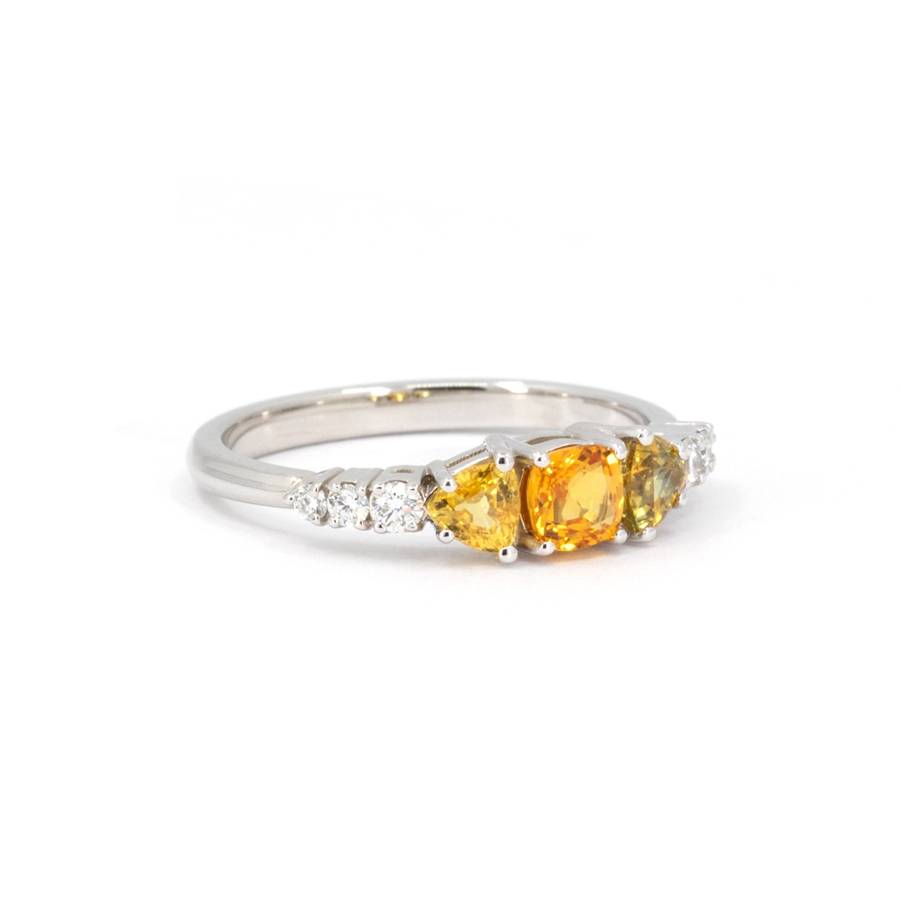 Side view of a bridal white gold ring with orange sapphires and lab grown diamonds, photographed on a white background. This jewel was handmade in Montreal by Bena Jewelry.