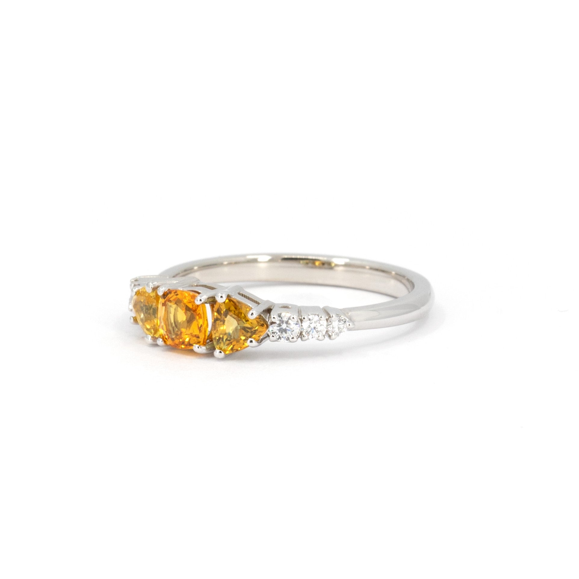 Product photography of a unique alternative engagement ring designed in Montreal by local brand Bena Jewelry. The white gold ring is seen on a white background. It features orange sapphires and diamonds.