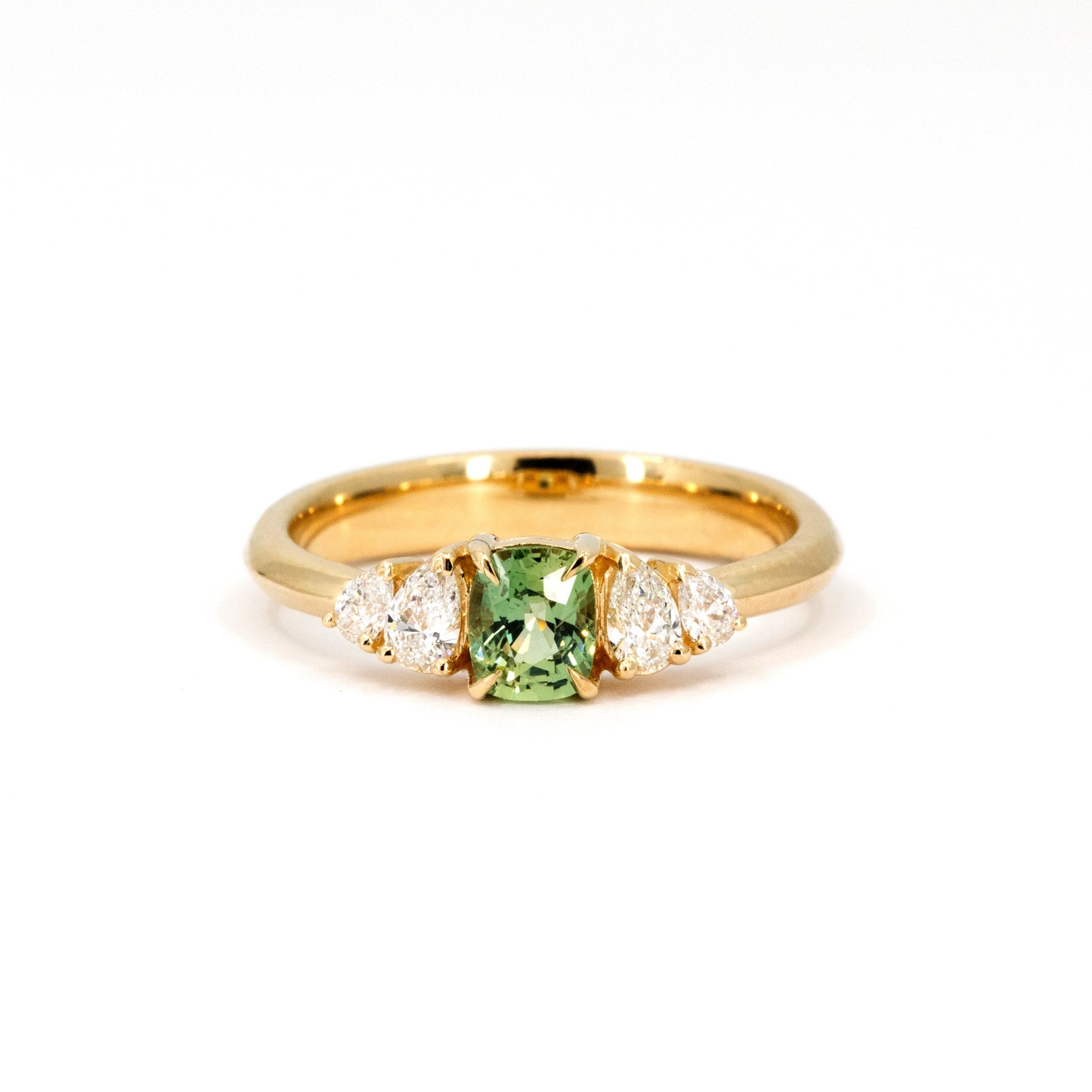 Cushion-cut green sapphire ring with lab-grown pear-shaped diamonds, set in yellow gold. Made by Bena Jewelry, Montreal, Canada.