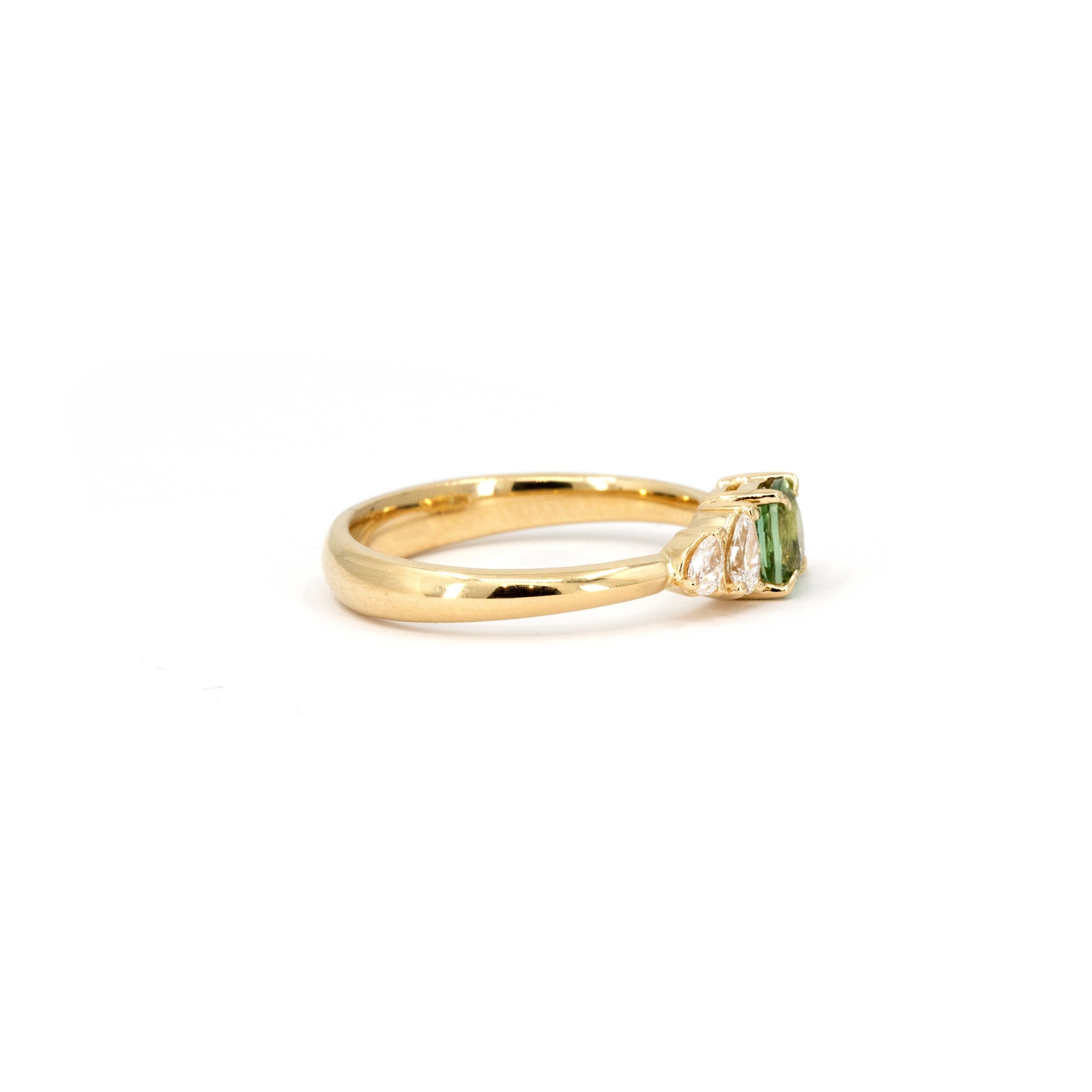 Cushion green sapphire center stone with pear-shaped lab diamonds on a yellow gold band. Crafted in Montreal by Canadian designer Bena Jewelry.