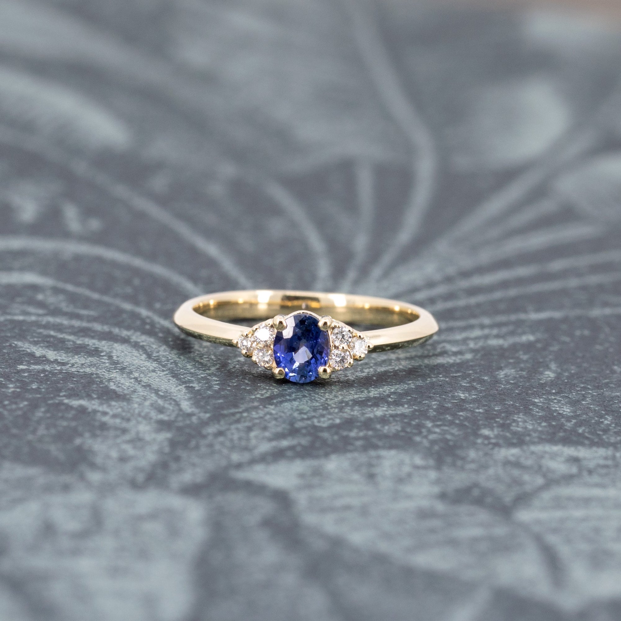 Artistic shot of the Desir Ring with a deep blue sapphire and diamonds, set in yellow gold, crafted by Bena Jewelry in Montreal.