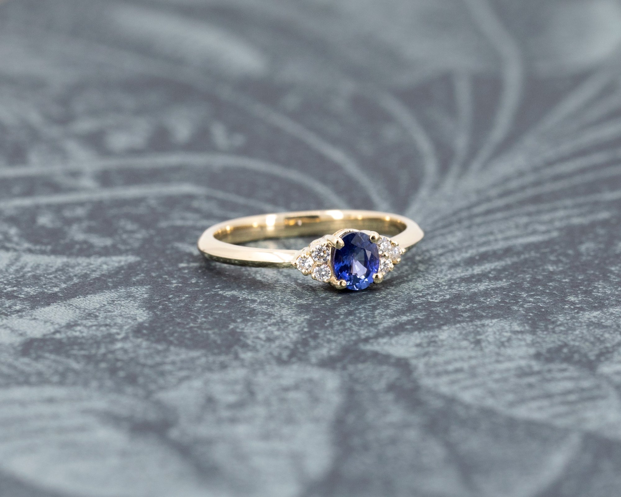 The Desir Ring, a custom sapphire and diamond engagement ring, beautifully displayed on a soft-colored surface. Designed in Canada.
