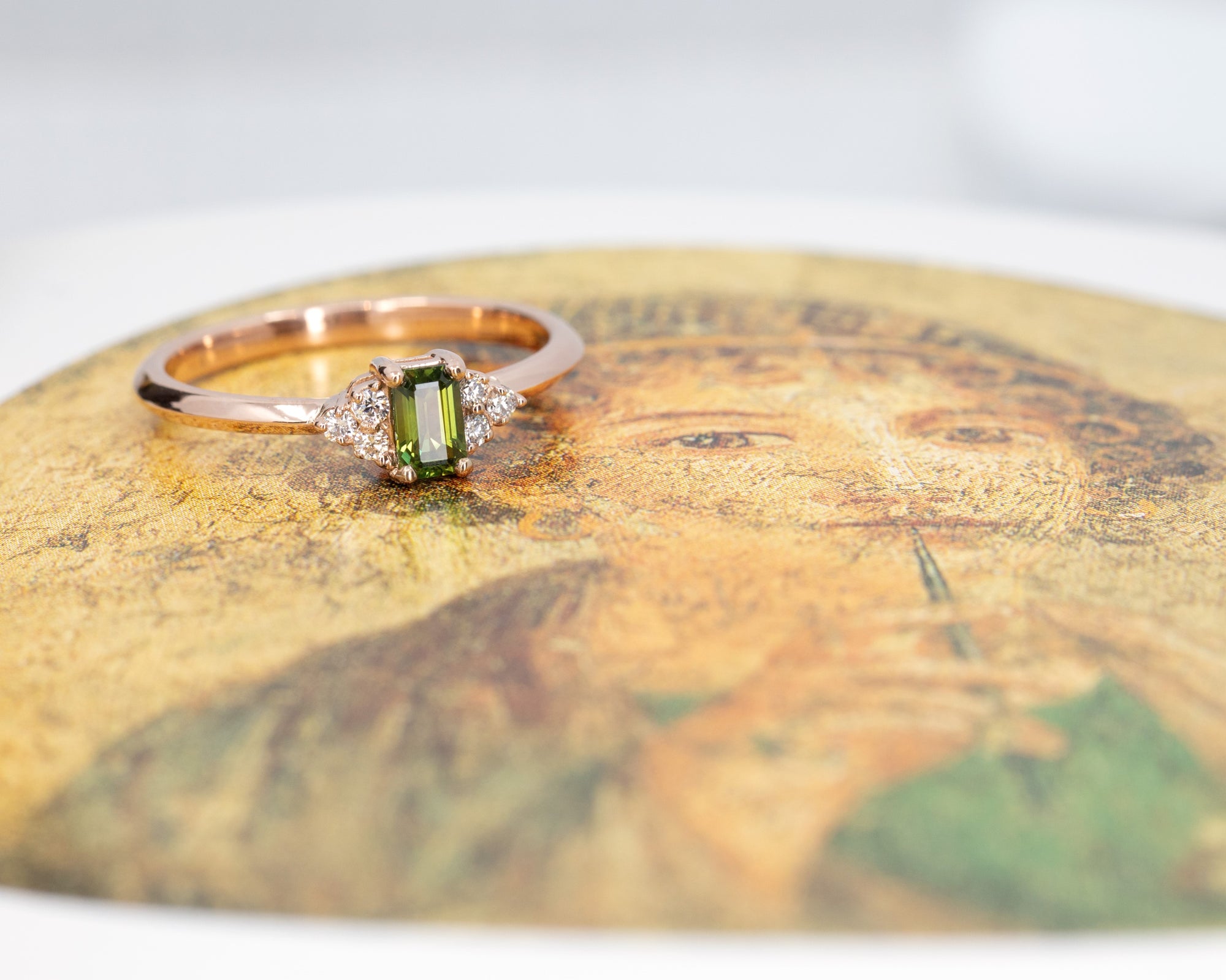 Désir Baguette Green Sapphire Ring in rose gold featuring a baguette-cut sapphire and diamonds by Bena Jewelry photographed on a dark background bespoke bridal jewelry made in Montreal