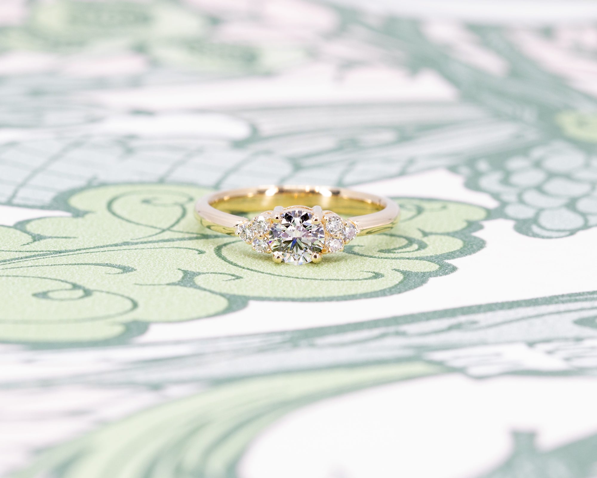 Elegant round diamond engagement ring in yellow gold with sparkling side stones, handmade by Bena Jewelry in Montreal.