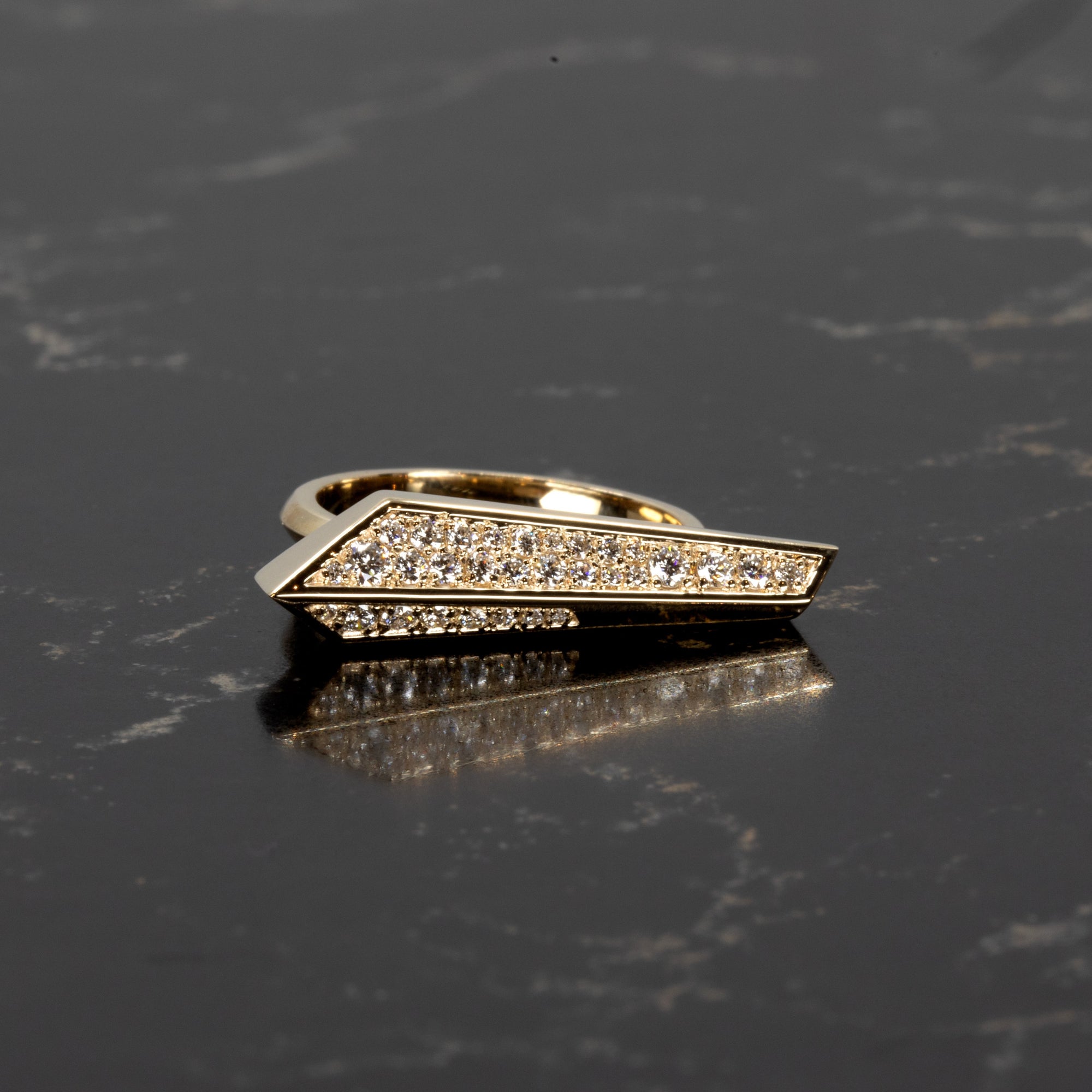 Bena Jewelry diamond ring in yellow gold displayed on a dark background, highlighting the bold lines and pavé-set brilliance of this sculptural design.