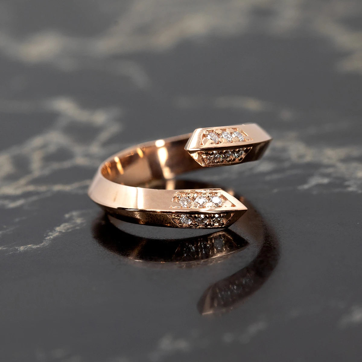 The edgy Loop Ring in rose gold and diamonds, by Bena Jewelry photographed on a deep charcoal surface to accentuate its bold, modern design. Handcrafted in Quebec.