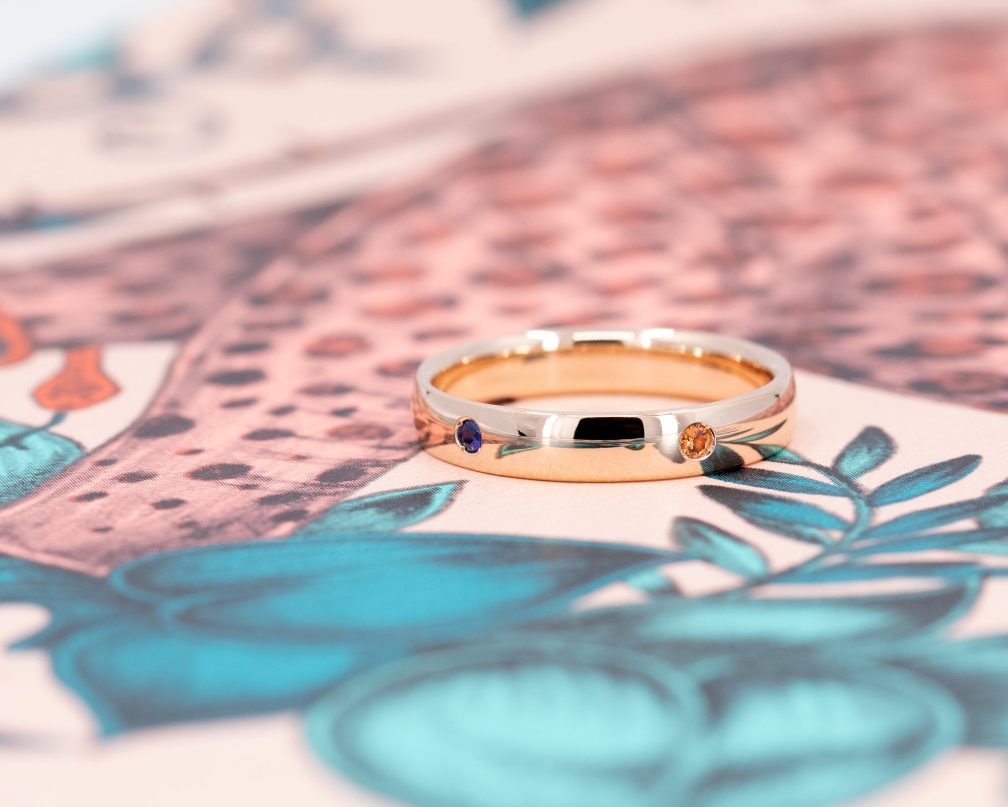 Sleek men&#39;s wedding band in rose gold with colorful gemstones Multi Colored Gemstone Band by Bena Jewelry displayed on a black matte background