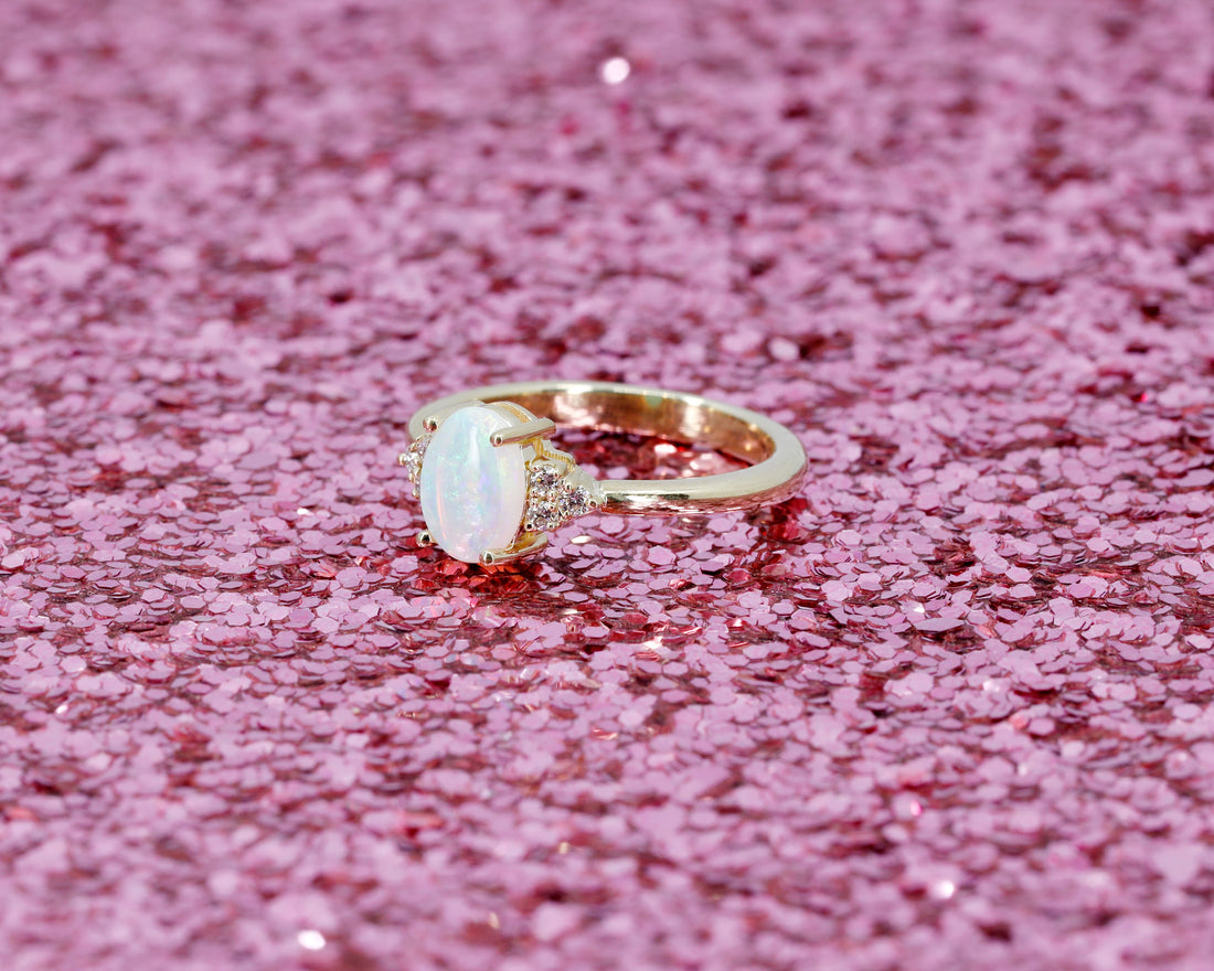 side view of custom made engagement ring in montreal by bena jewlery yellow gold ring opal and diamond on glitter background