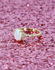 side view of custom made engagement ring in montreal by bena jewlery yellow gold ring opal and diamond on glitter background