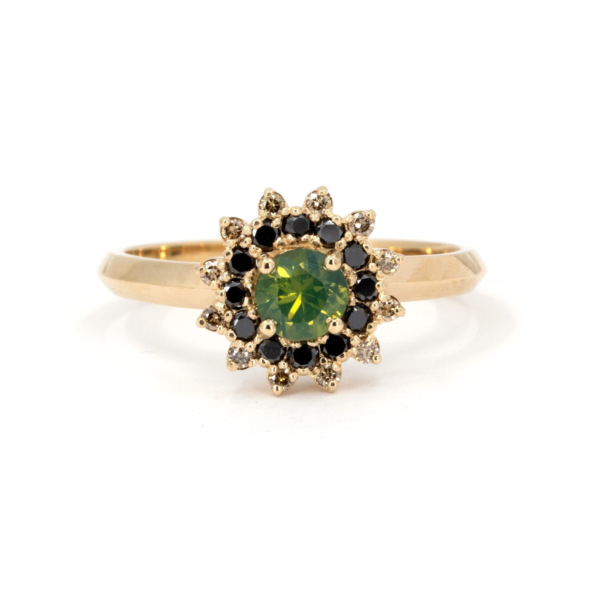 Bena Jewelry ring designed in Montreal, featuring a round opalescent green sapphire with a starburst halo of black and brown diamonds, set in 14k yellow gold on a white background.