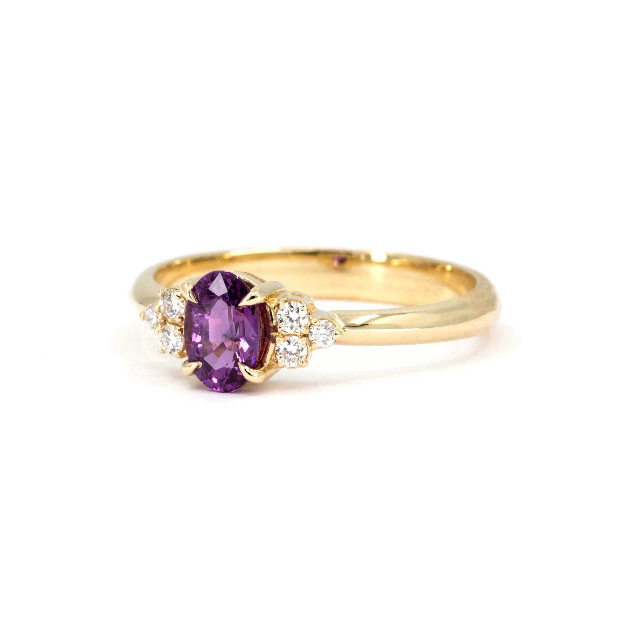 Close-up of the purple-pink sapphire Desir Ring in yellow gold, showcasing its elegant eagle-claw prong setting. Made in Canada by Bena Jewelry.