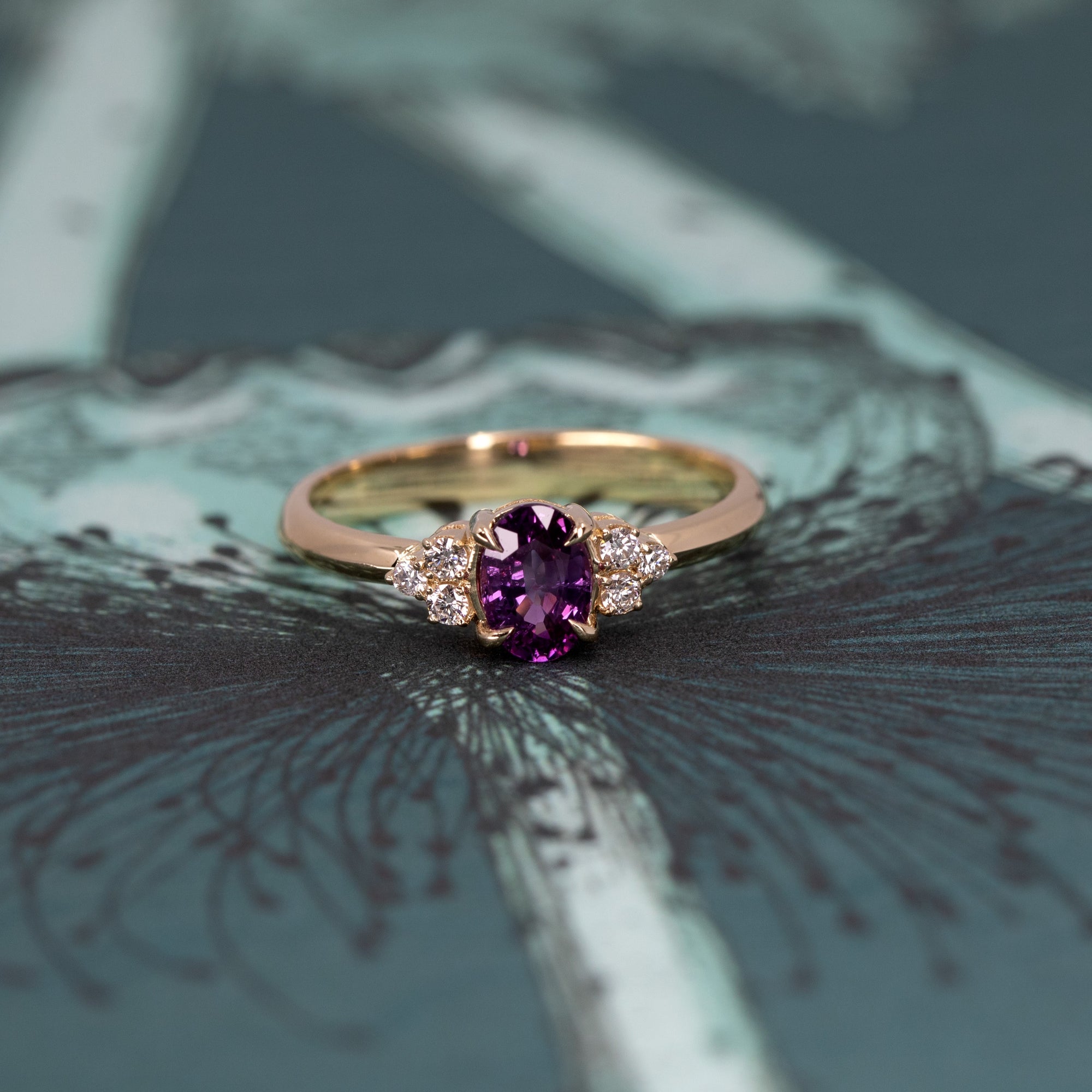 The Desir Ring, a custom sapphire and diamond engagement ring, elegantly displayed on a soft-colored surface. Designed in Canada.