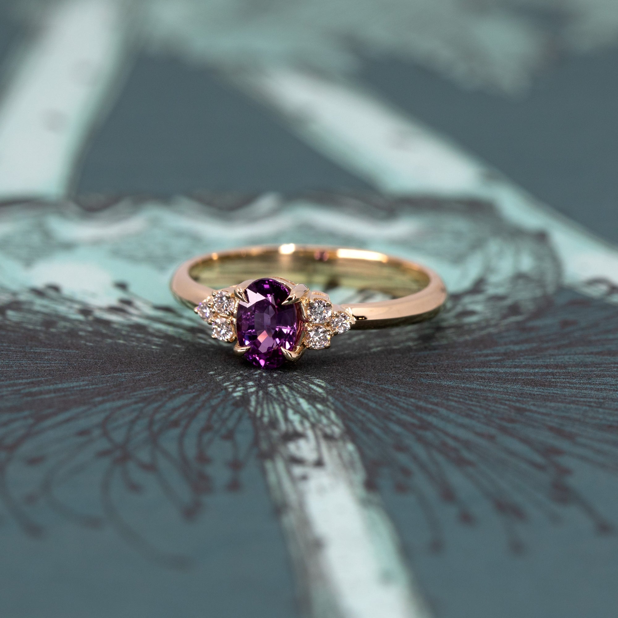 Artistic shot of the Desir Ring with a vibrant purple-pink sapphire and diamonds, set in yellow gold, crafted by Bena Jewelry in Montreal.