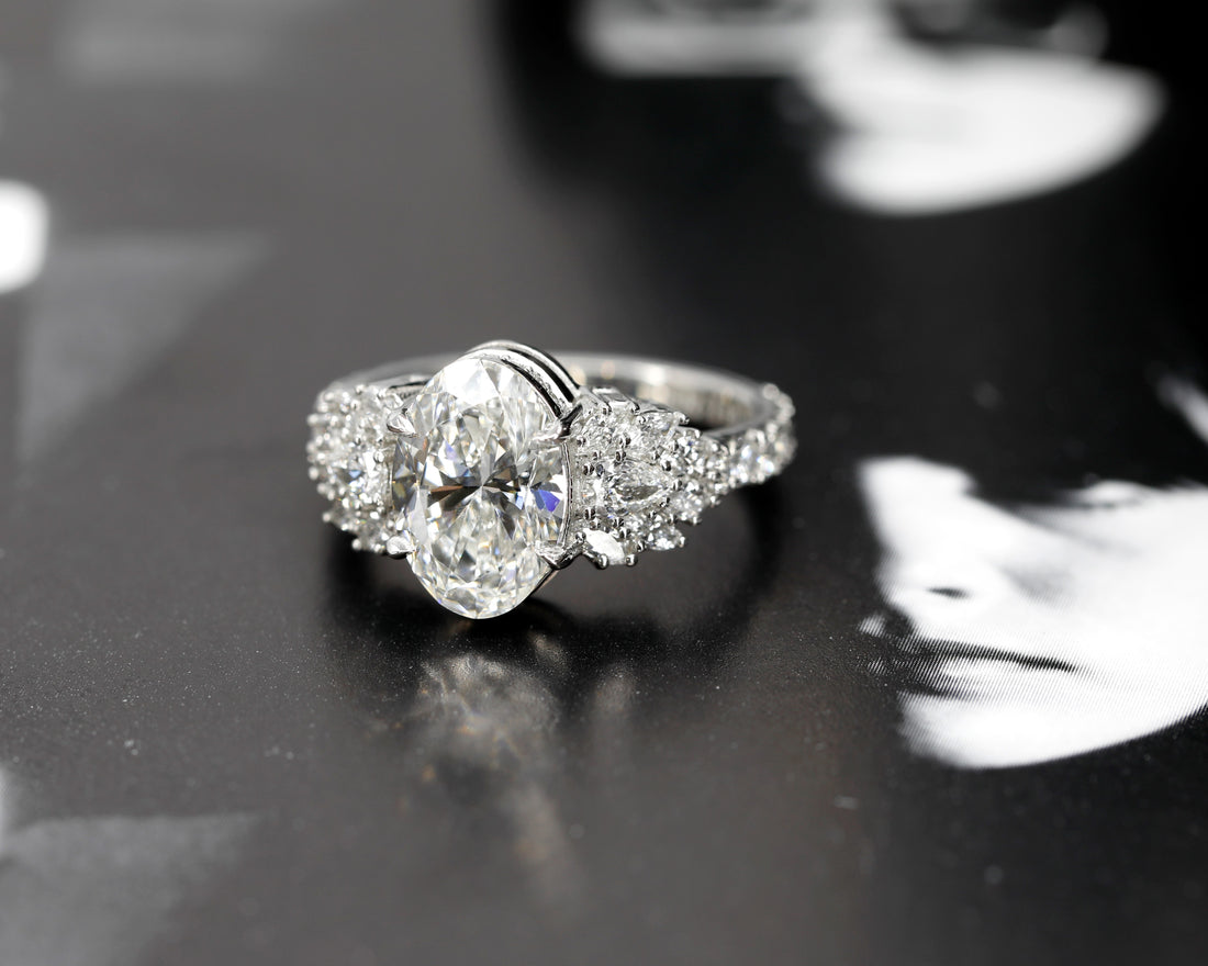 side view of oval shape bridal engagement ring custom made in montreal with central oval shape lab grown diamnonds and marquise pear shape side natural gems on dark background