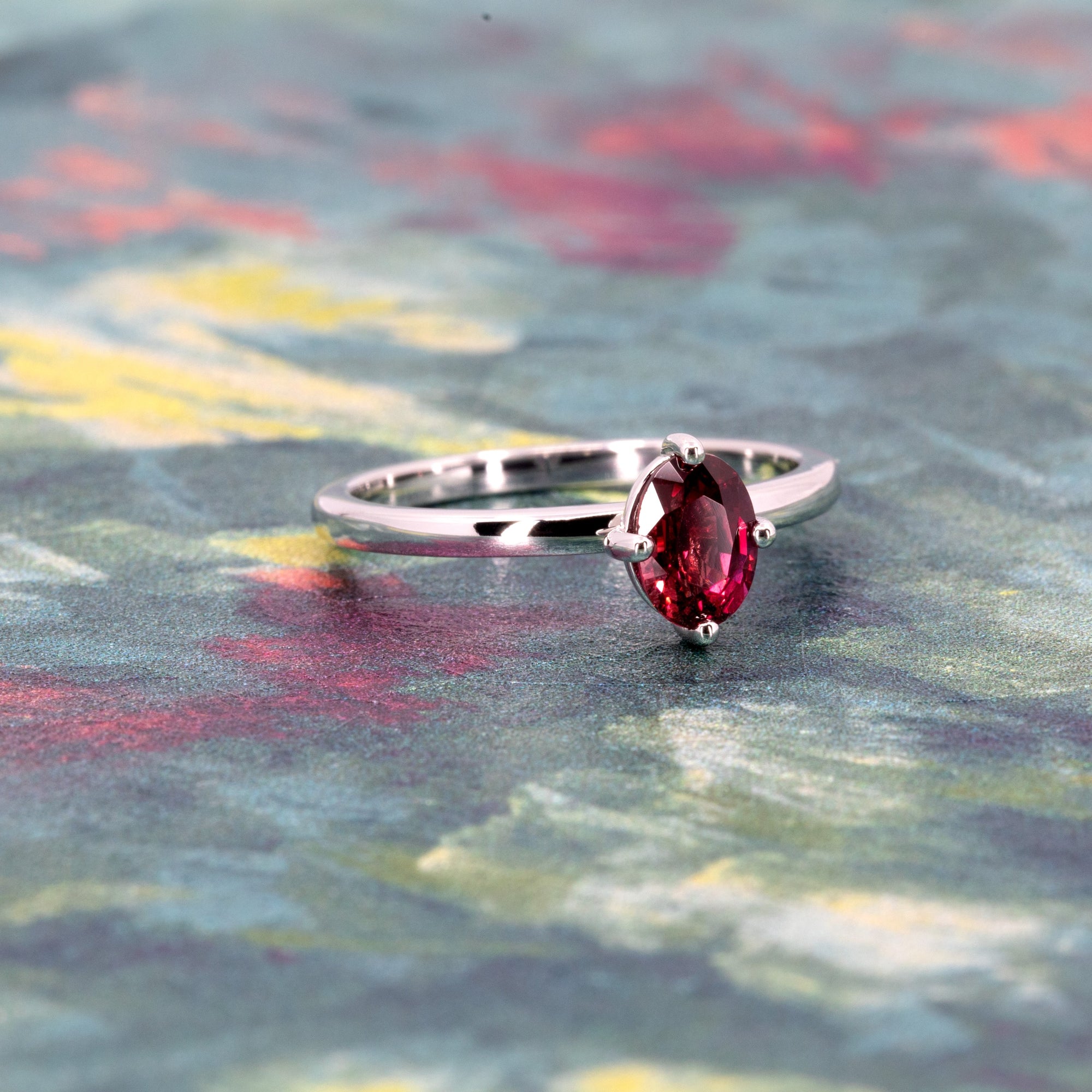 Elegant white gold ring with deep red ruby photographed on a bold color background, handmade in Montreal by Bena Jewelry.