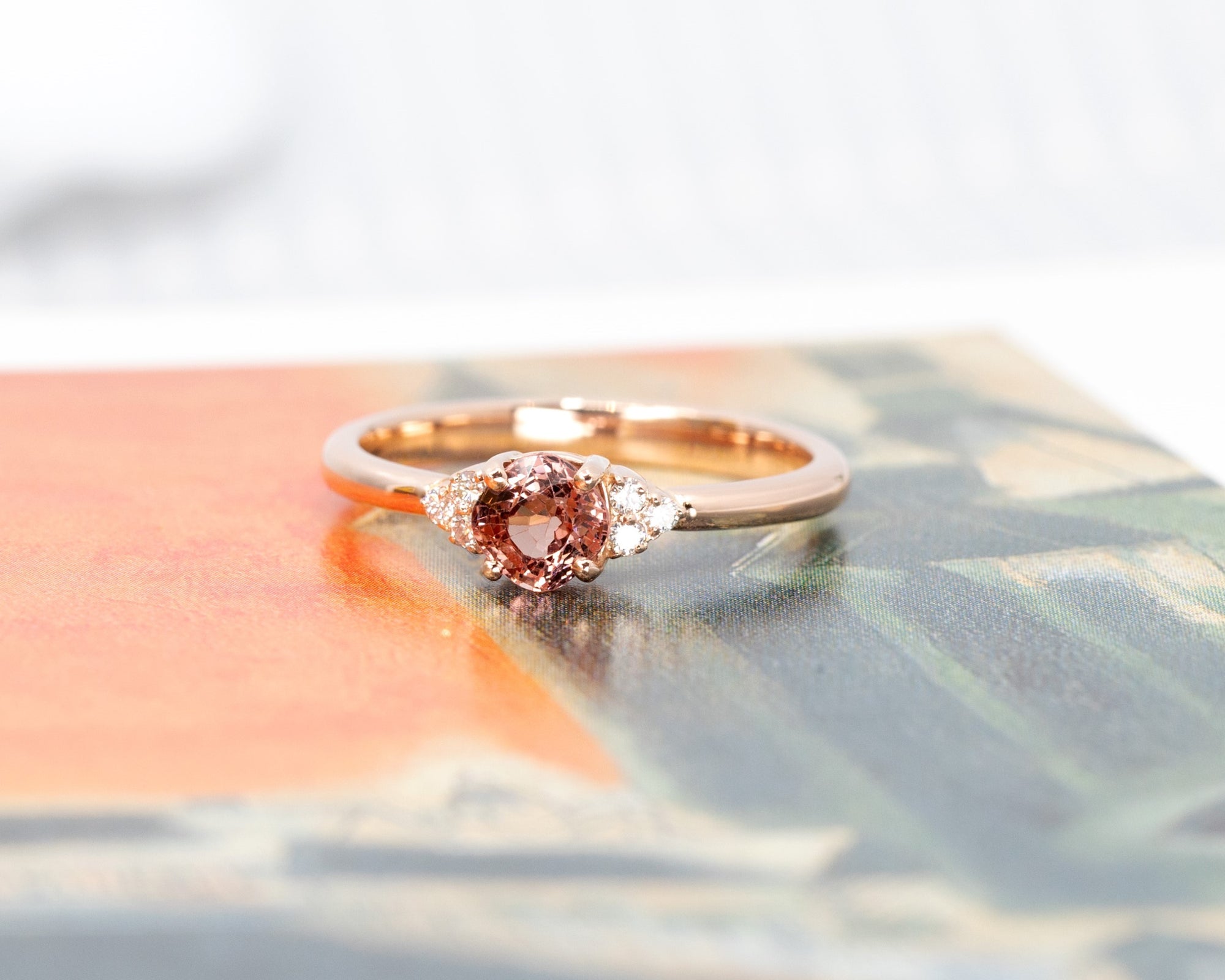 The Désir ring glows in a colorful setting, emphasizing the unique blend of its peach spinel, diamond accents, and luxurious rose gold craftsmanship.