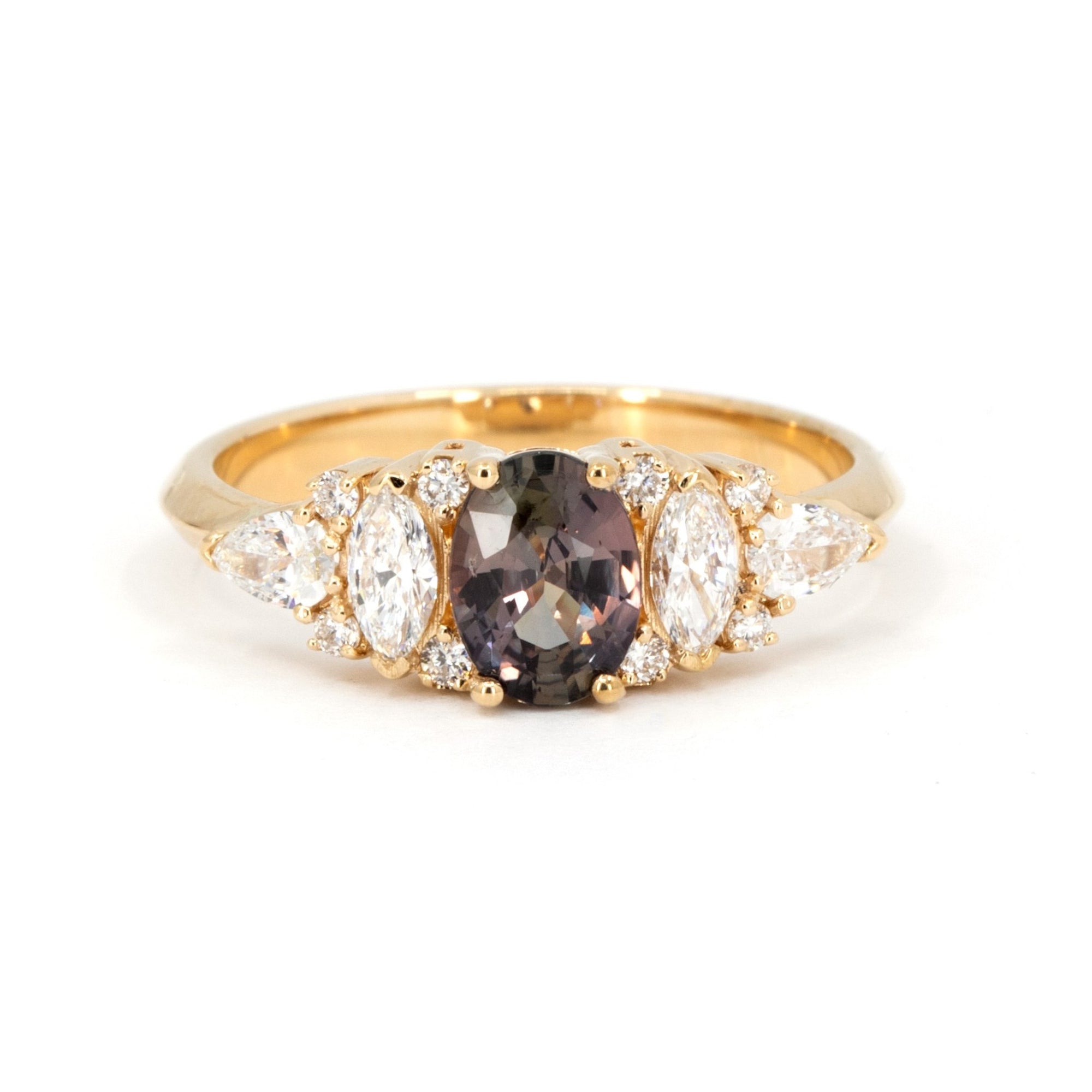 Bena Jewelry engagement ring with oval peacock sapphire and white marquise, pear, and round diamonds on a 14k yellow gold band, photographed on white background.