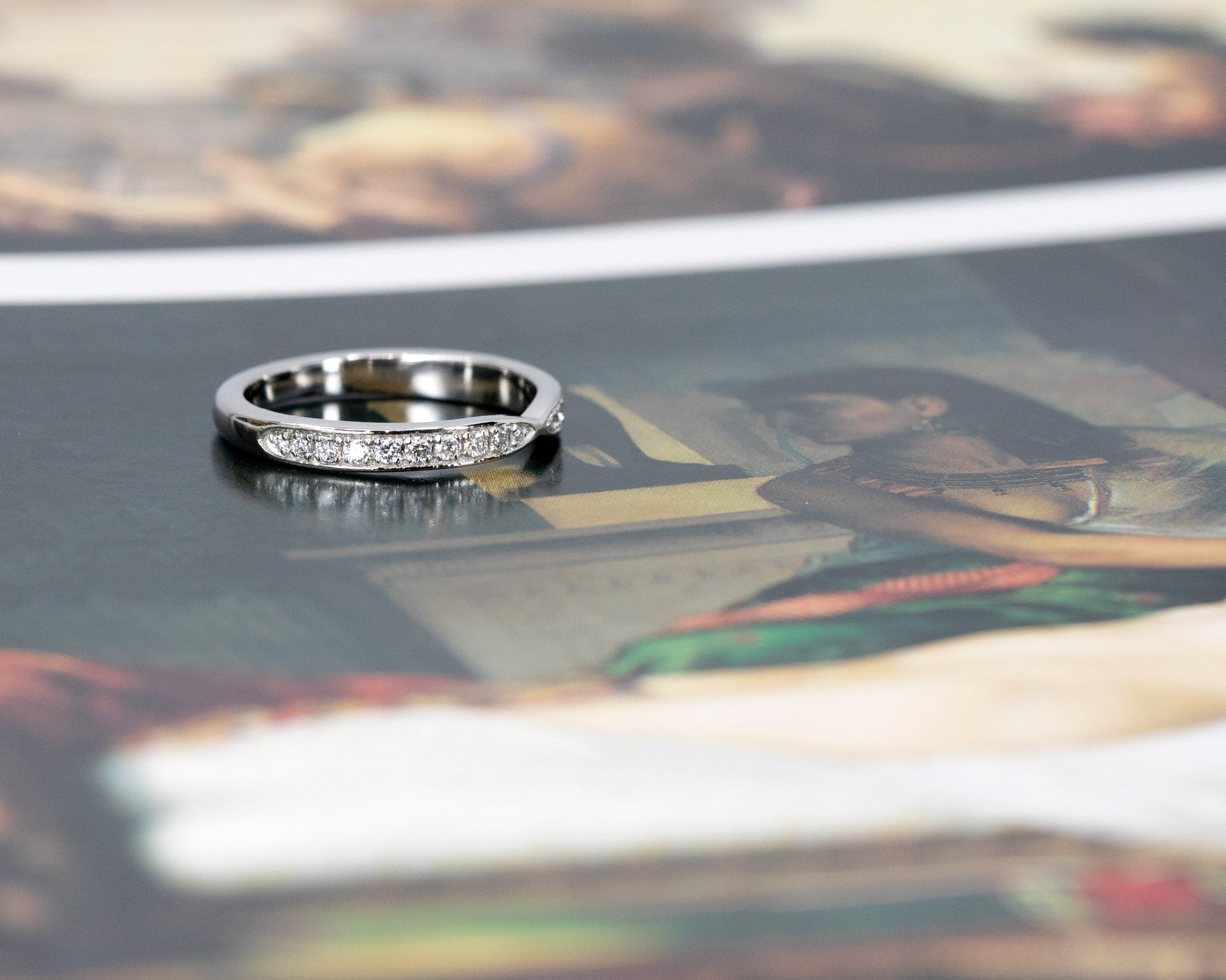 Platinum wedding band with diamonds and a modern pinch design, shown on a soft-colored background. Made in Montreal by Bena Jewelry.