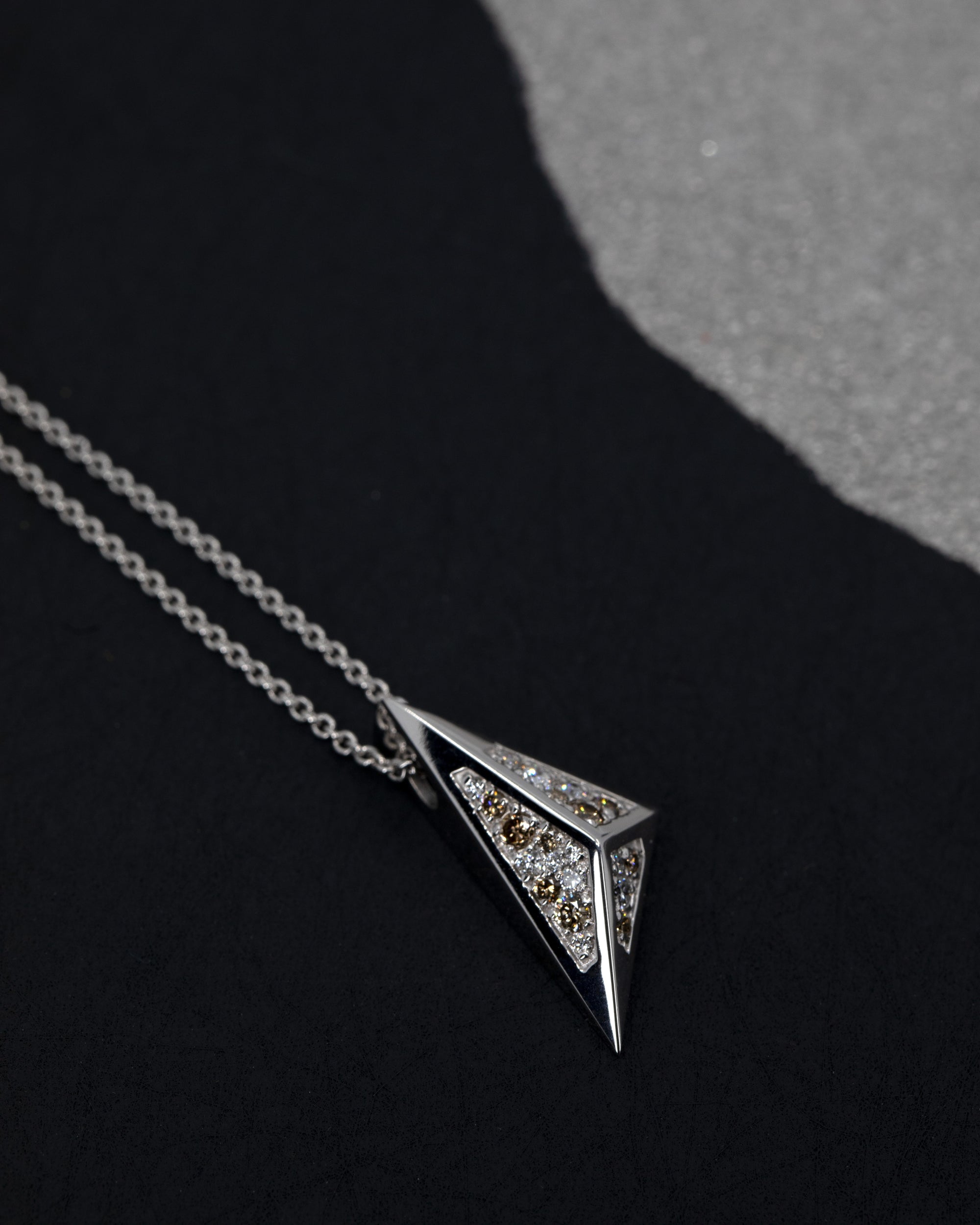 Bold geometric pendant in white gold, featuring golden-brown and white diamonds, glowing against a dark backdrop. Handmade in Montreal by Bena Jewelry.