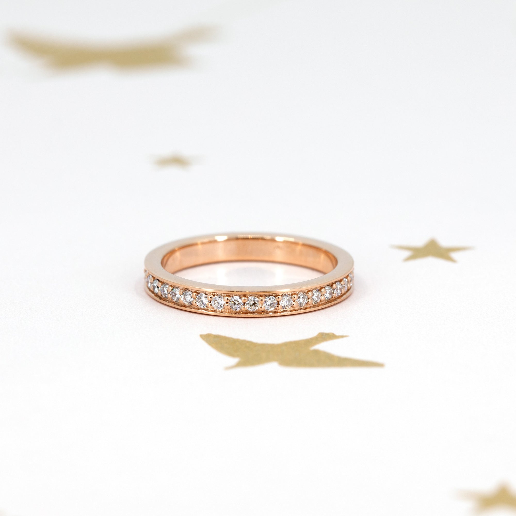 Rose gold wedding band with pinpoint-set lab-grown diamonds, worn on the hand to showcase its brilliant shine. Perfect for stacking with other rings, handcrafted by Bena Jewelry in Montreal.