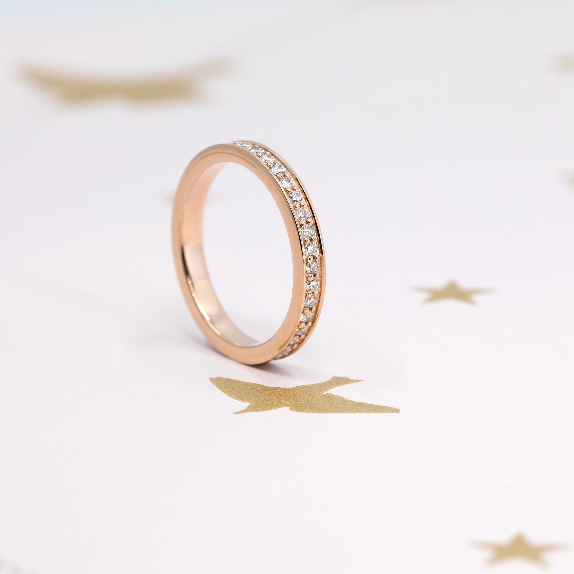 Flat lay featuring Bena Jewelry’s rose gold wedding band with pinpoint-set lab-grown diamonds, paired with other stacking rings. Handcrafted in Montreal, Quebec, for a luxurious, personalized ring collection.