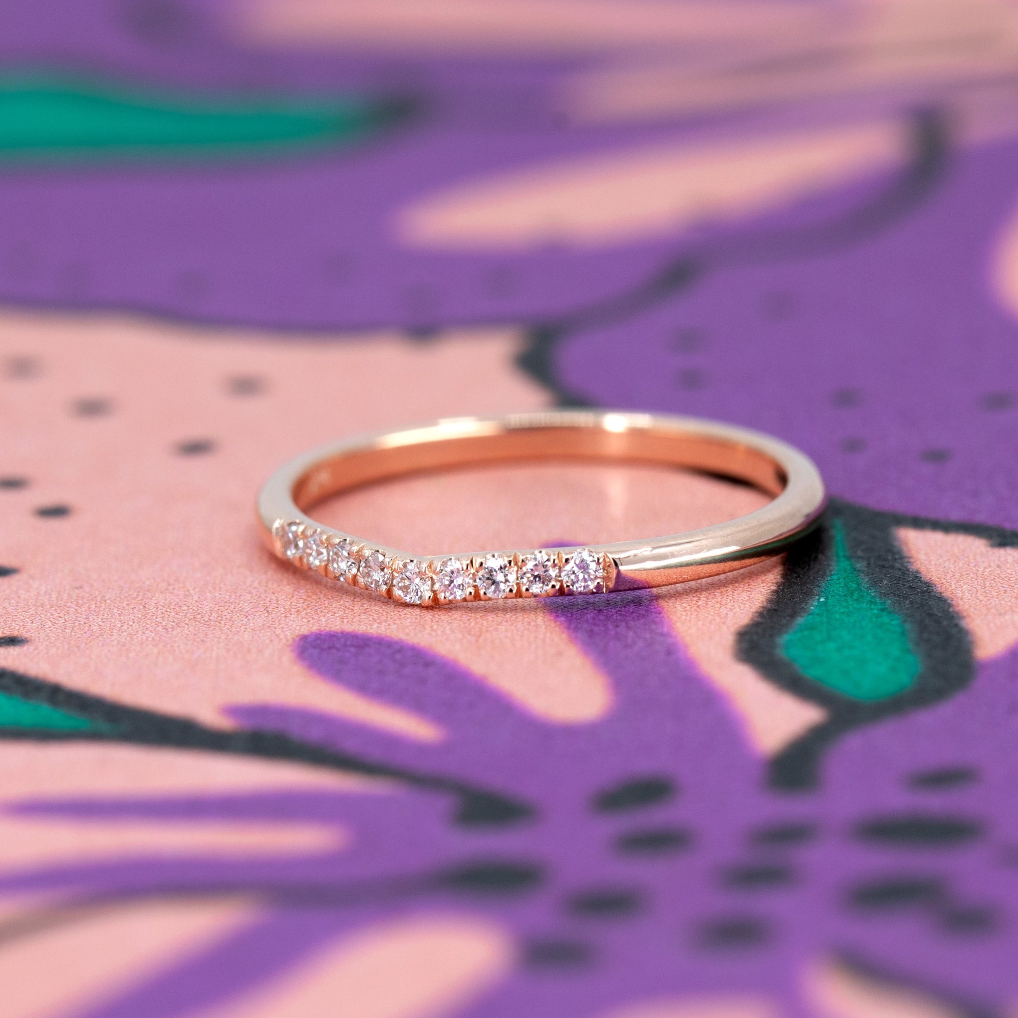 Elegant shot of the Luna Band by Bena Jewelry, featuring a graceful curve with pavé-set diamonds. A modern wedding or stacking ring in rose gold.