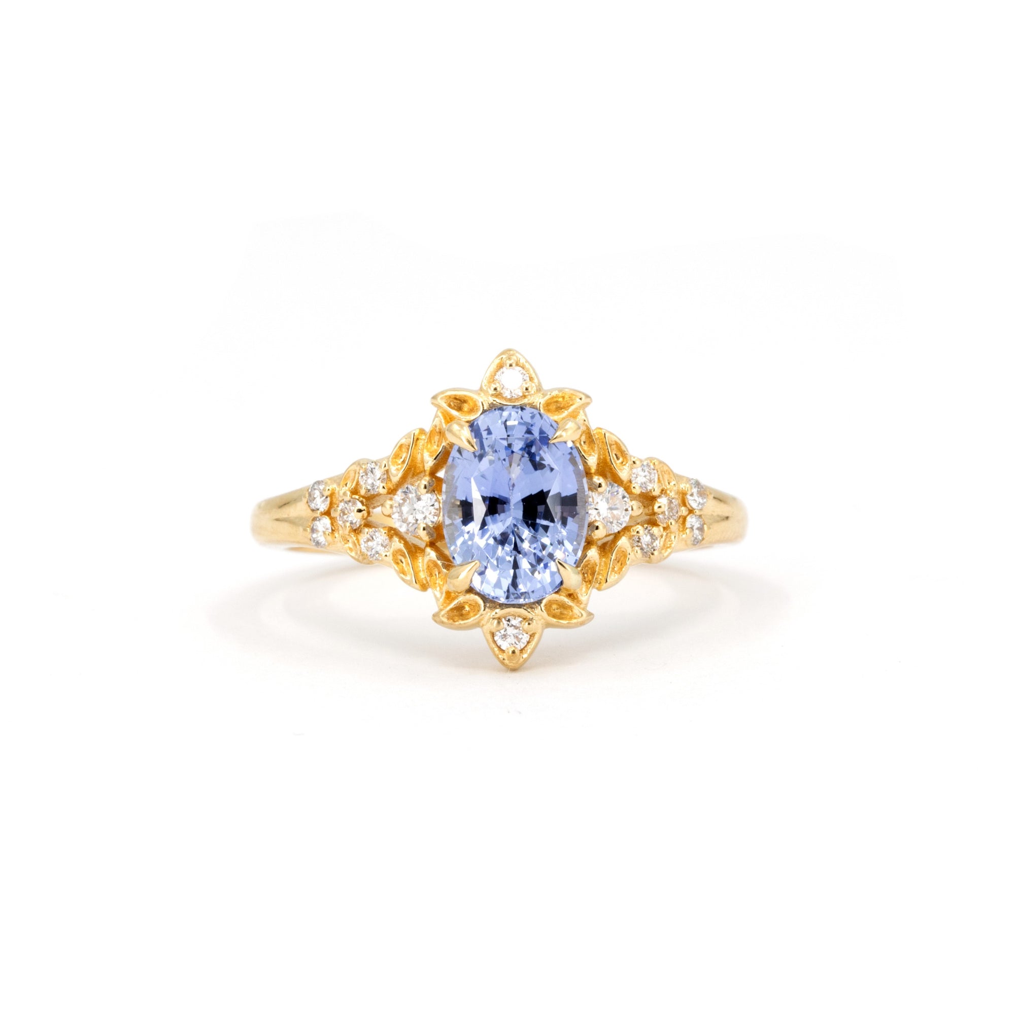 Sky Bloom Oval Sapphire Ring on white background – A floral-inspired engagement ring featuring a brilliant sky-blue oval sapphire in yellow gold. Handmade by Bena Jewelry in Montreal.