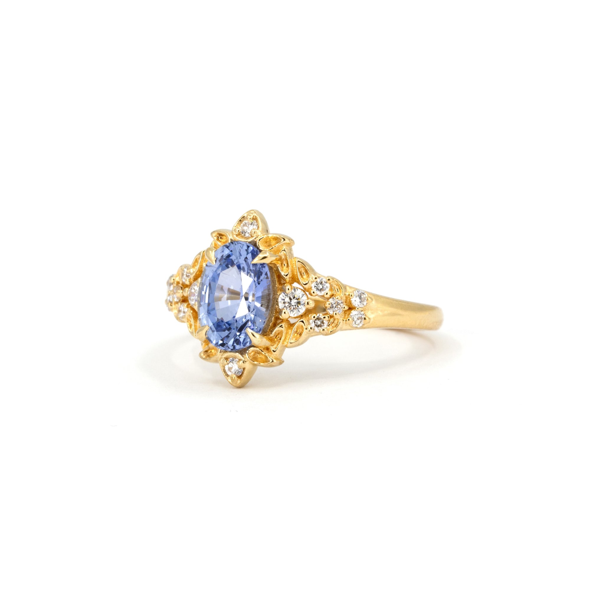 Top-down view of sapphire and gold ring – A dreamlike, custom-made engagement ring with a floral design and a luminous sapphire centerpiece.