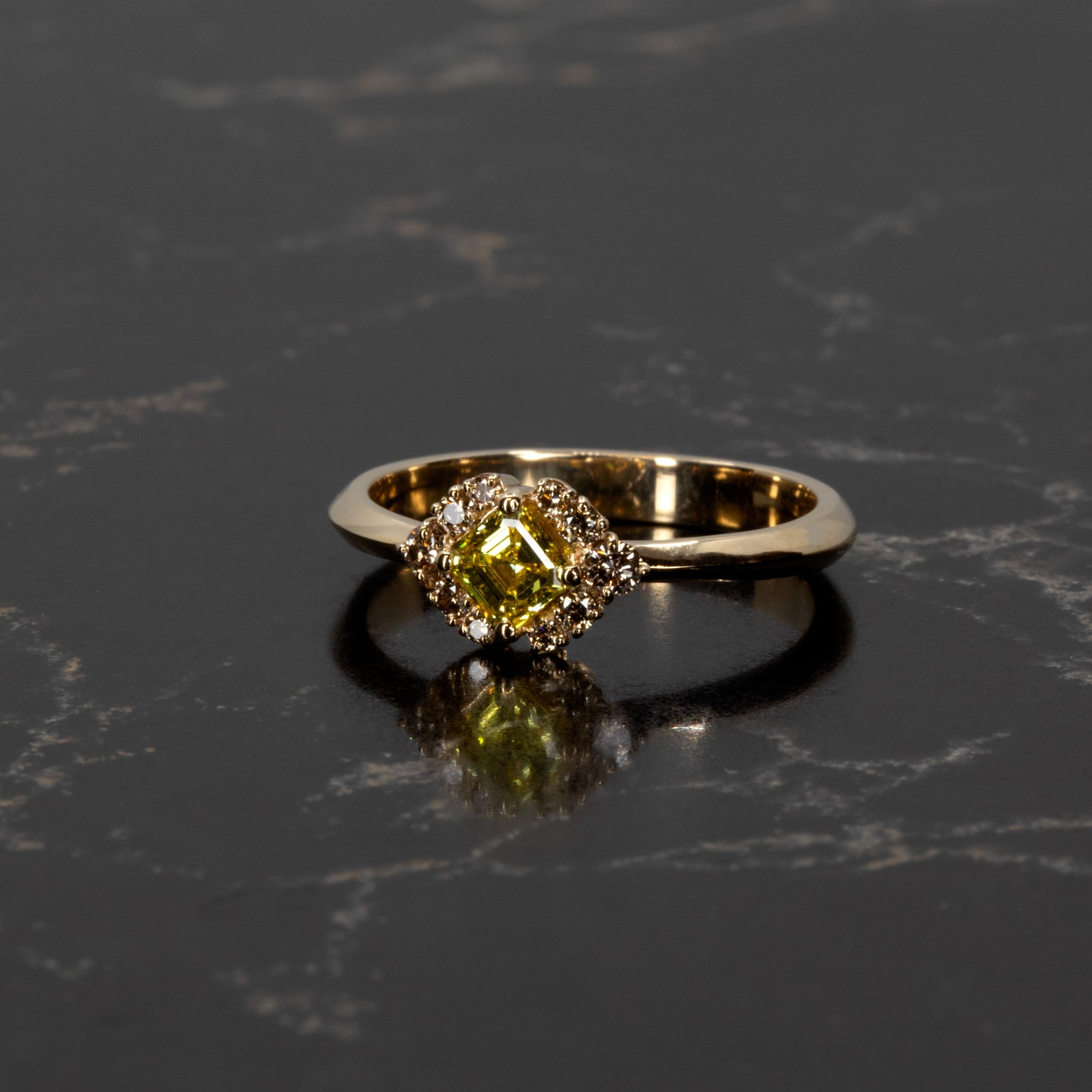 Bena Jewelry&#39;s Asscher-cut yellow diamond ring glowing against a dark background, emphasizing the golden tones and intricate brown diamond halo, handmade in Canada.