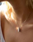 Close-up of a woman wearing a modern 14k white gold pendant with pavé-set diamonds, featuring a bold geometric silhouette. Contemporary design by Bena Jewelry, available at Ruby Mardi in Montreal.