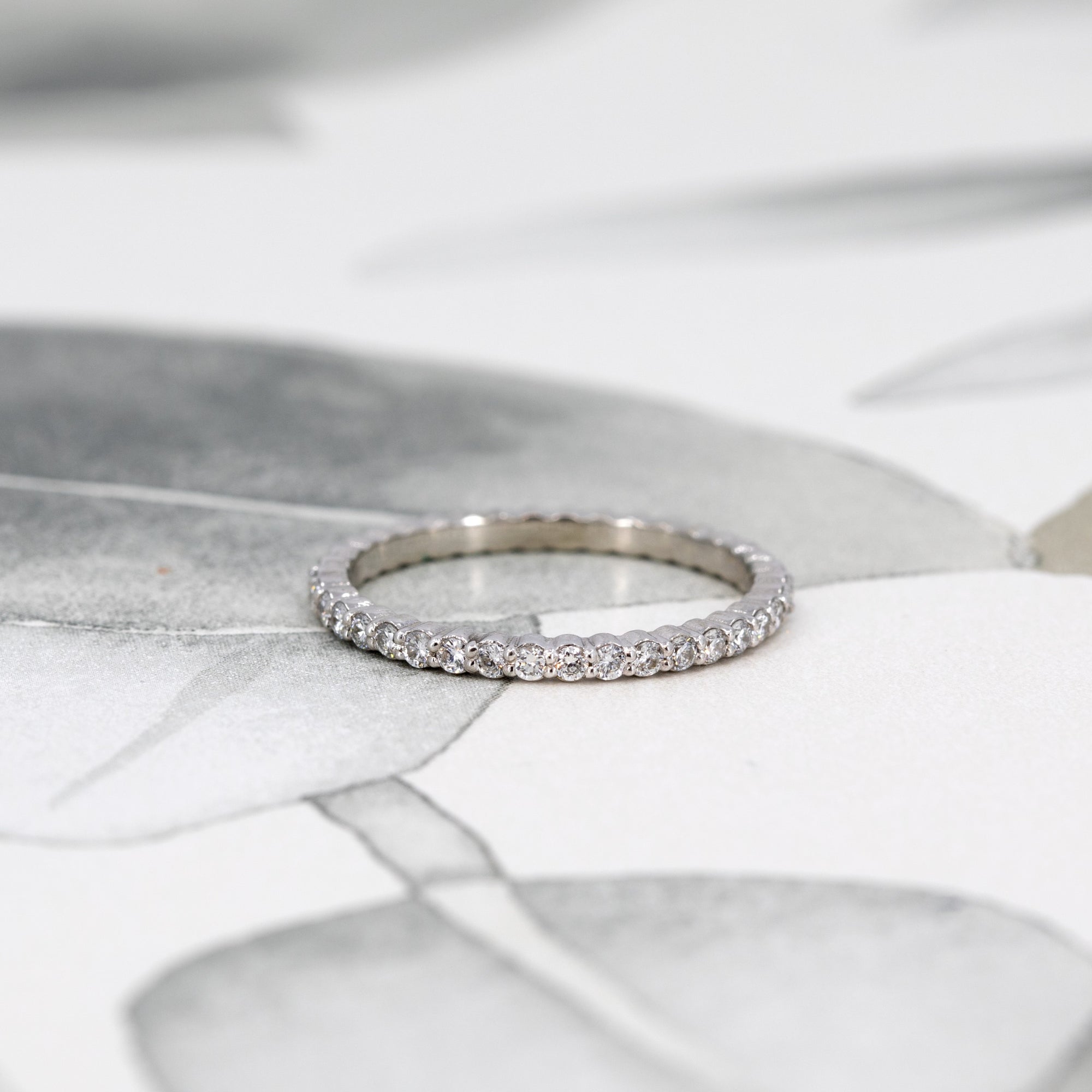 White gold eternity band styled to complement a diamond engagement ring. Designed by Bena Jewelry, this custom-made piece pairs classic elegance with a modern touch, handcrafted in Montreal.