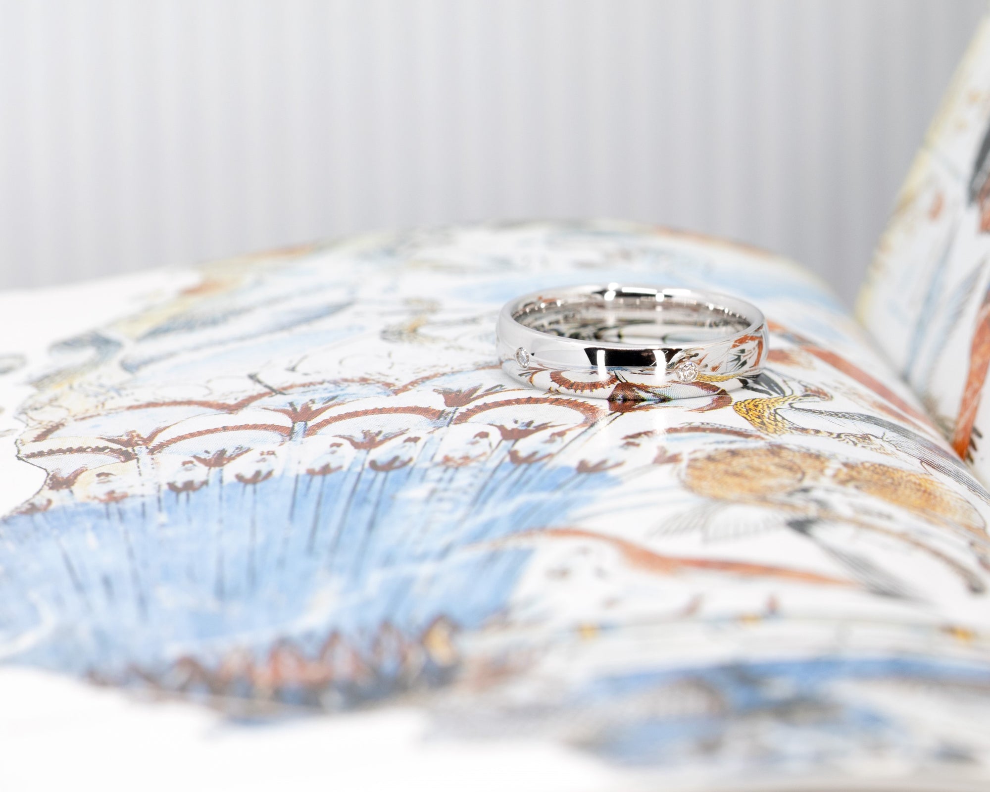 Elegant domed white gold wedding ring with bezel-set diamonds crafted by Bena Jewelry photographed on a vibrant background bespoke bridal jewelry made in Canada