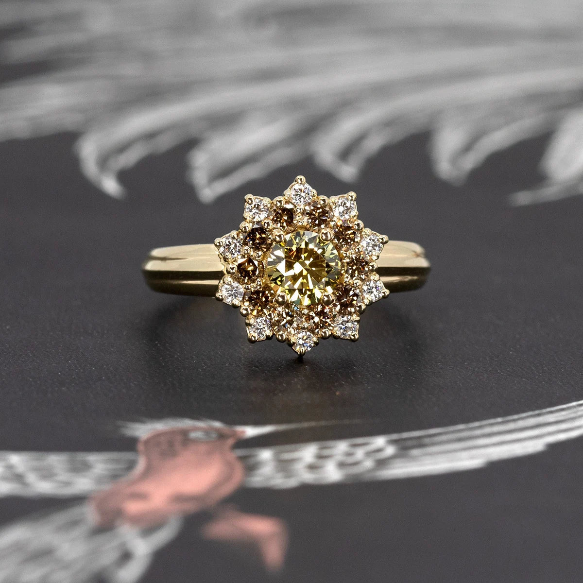 Close-up of the Soleil yellow diamond ring with a brown and white diamond halo, set in yellow gold, shown against a dark backdrop by Bena Jewelry.