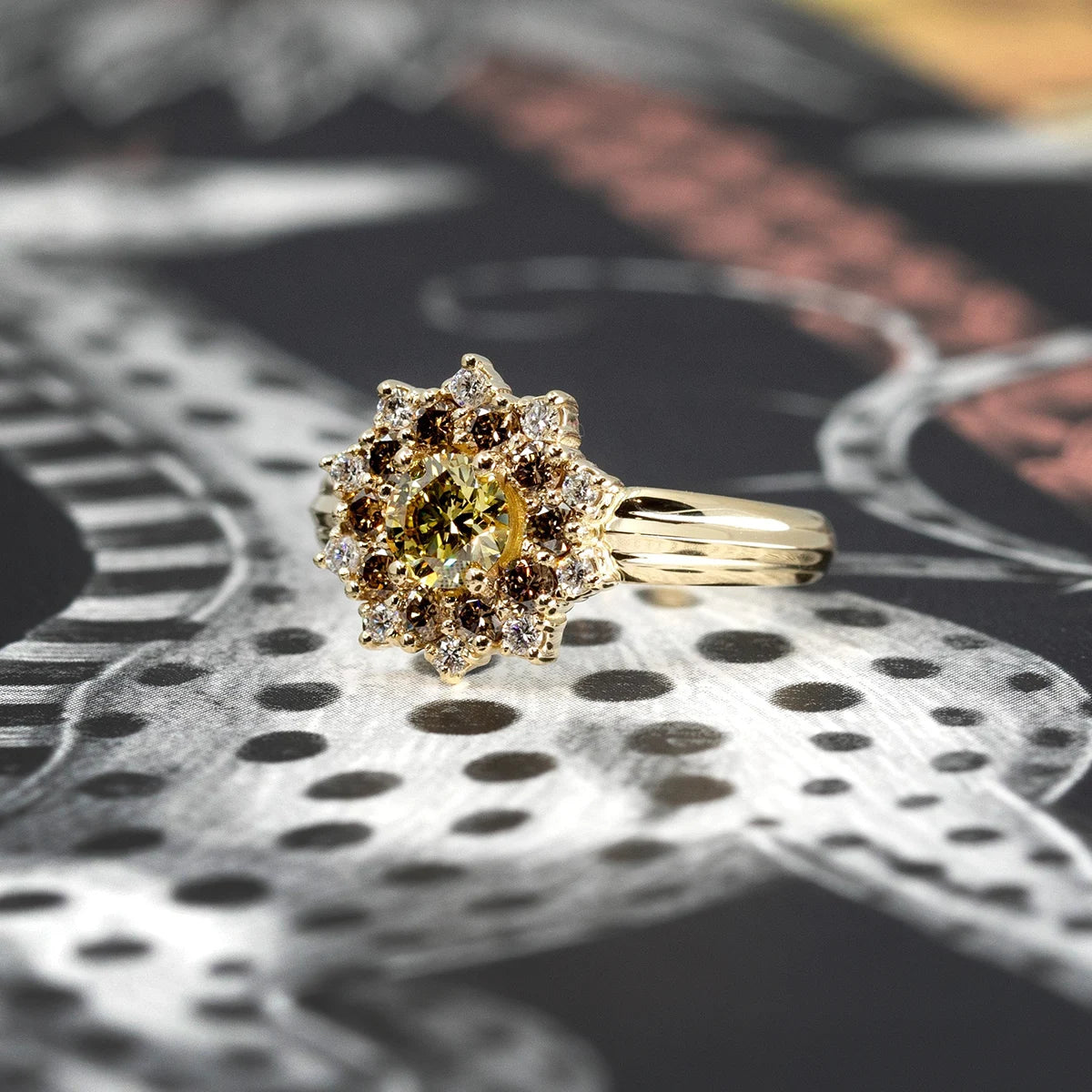 Side view product image of a sunburst ring set against a dark backdrop. This ring features a broad yellow gold band, highlighted by a round yellow laboratory diamond at its center, encircled by round gold/brown diamonds and sparkling white diamonds. Designed by independent fine jewelry designer Bena Jewelry.