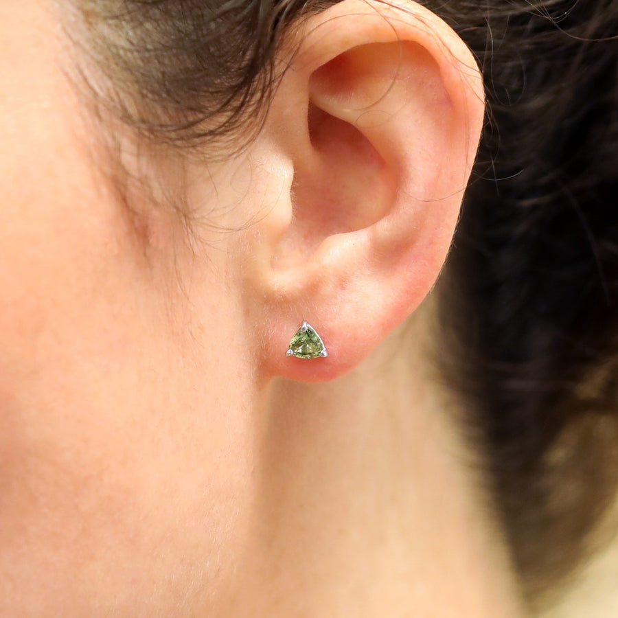 Girl's ear with green sapphire trillion shape gemstone studs earrings natural color gemstone custom made jewelry montreal specialist bridal ring small gemstone studs cocktail ring engagement ring little italy montreal Bena Jewelry jeweler designer