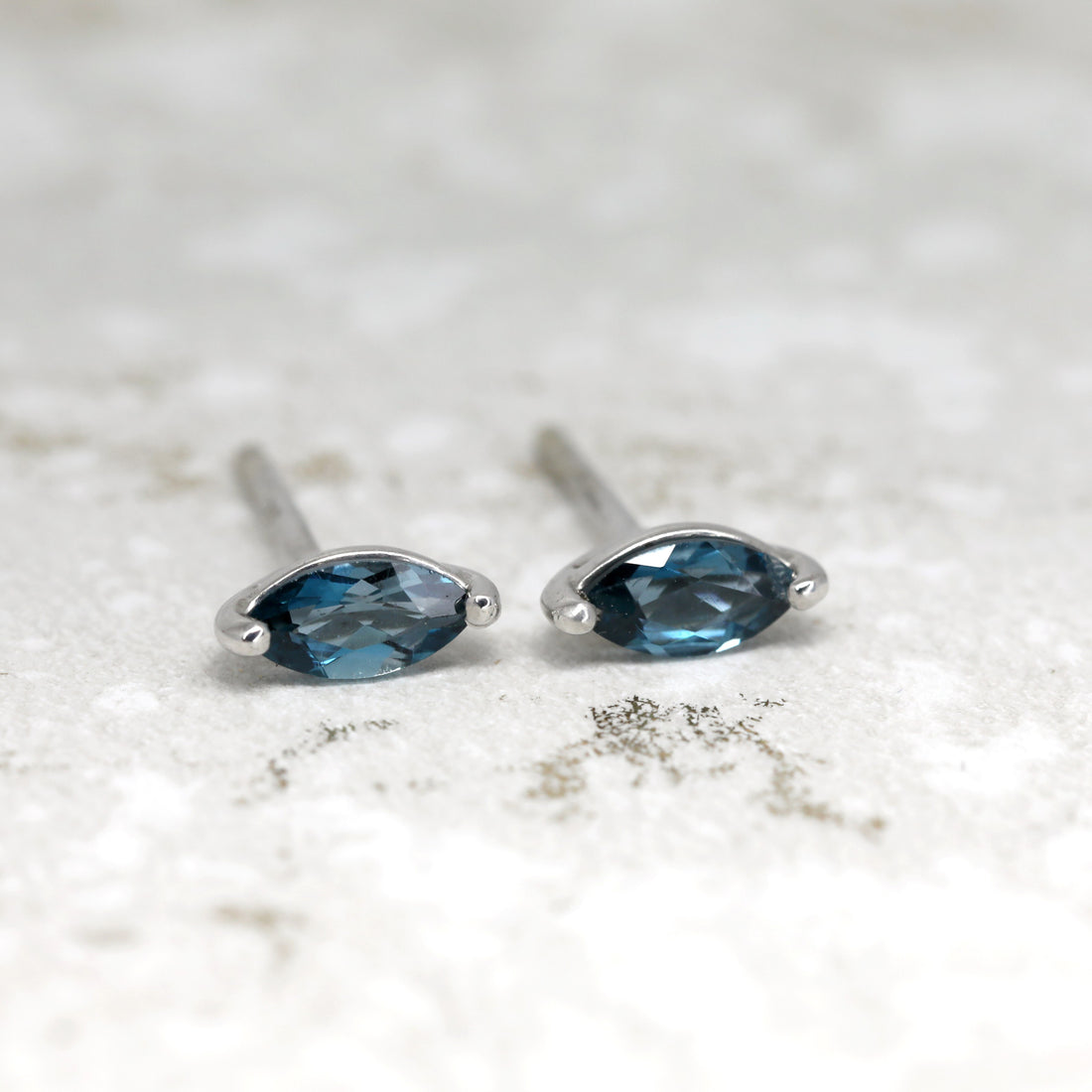 Front view of topaz london blue small earrings studs handmade in montreal fine jewelry designer marquise blue gemstone custom earrings gemstone specialist