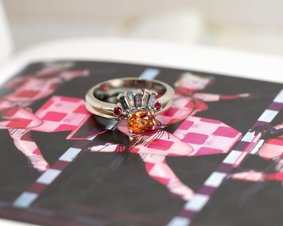 orange garnet engagement ring and salt pepper diamond wedding band made in montreal on a multi color background