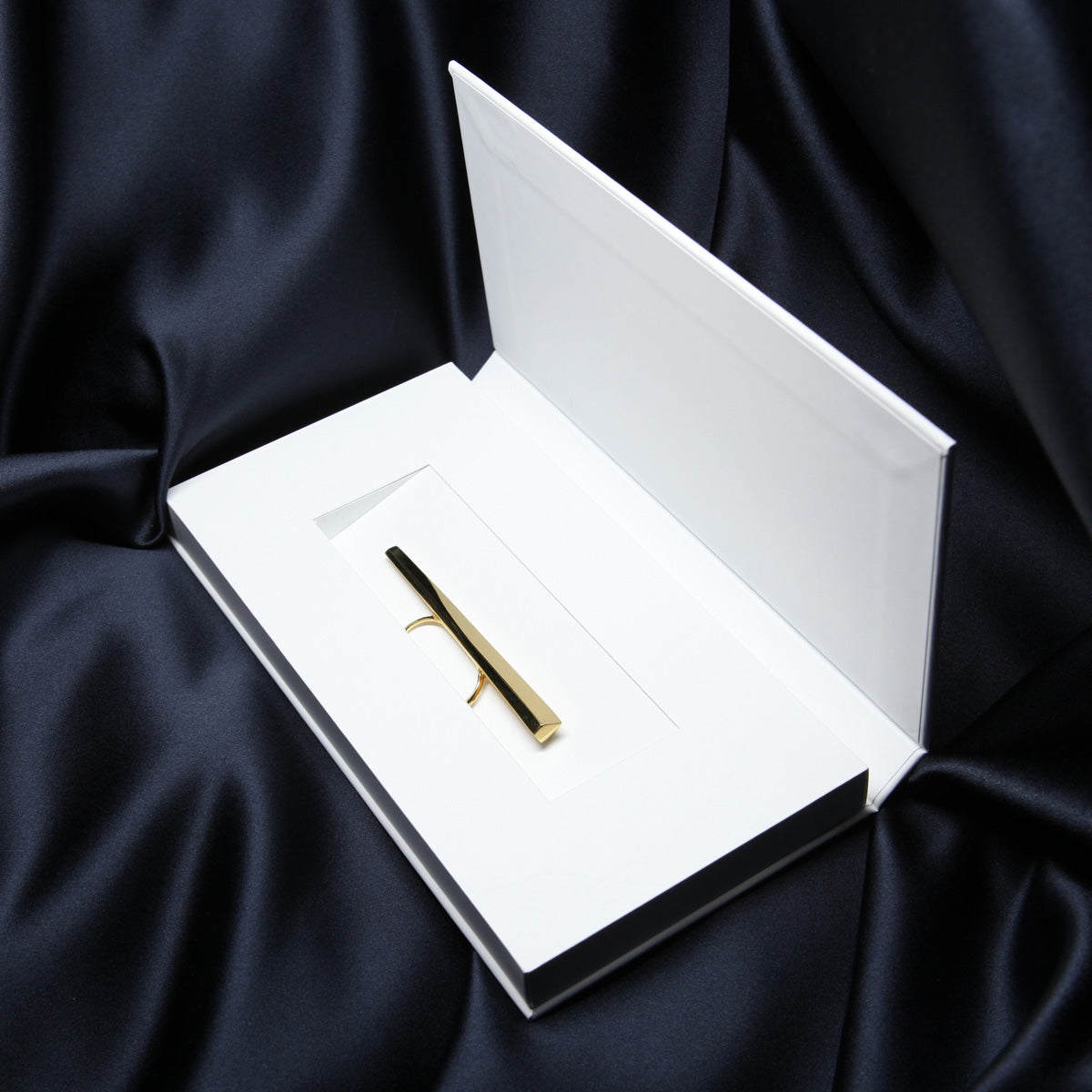 A solid gold ring with lots of character is seen placed in its box. The jewel consists of a long, shapely block of gold that runs the full width of the fist and is worn on two fingers with a comfortable double band. It&#39;s by Montreal-based designer Bena Jewelry, who creates modern, elegant, gender-neutral jewelry that reflects light in a unique way.
