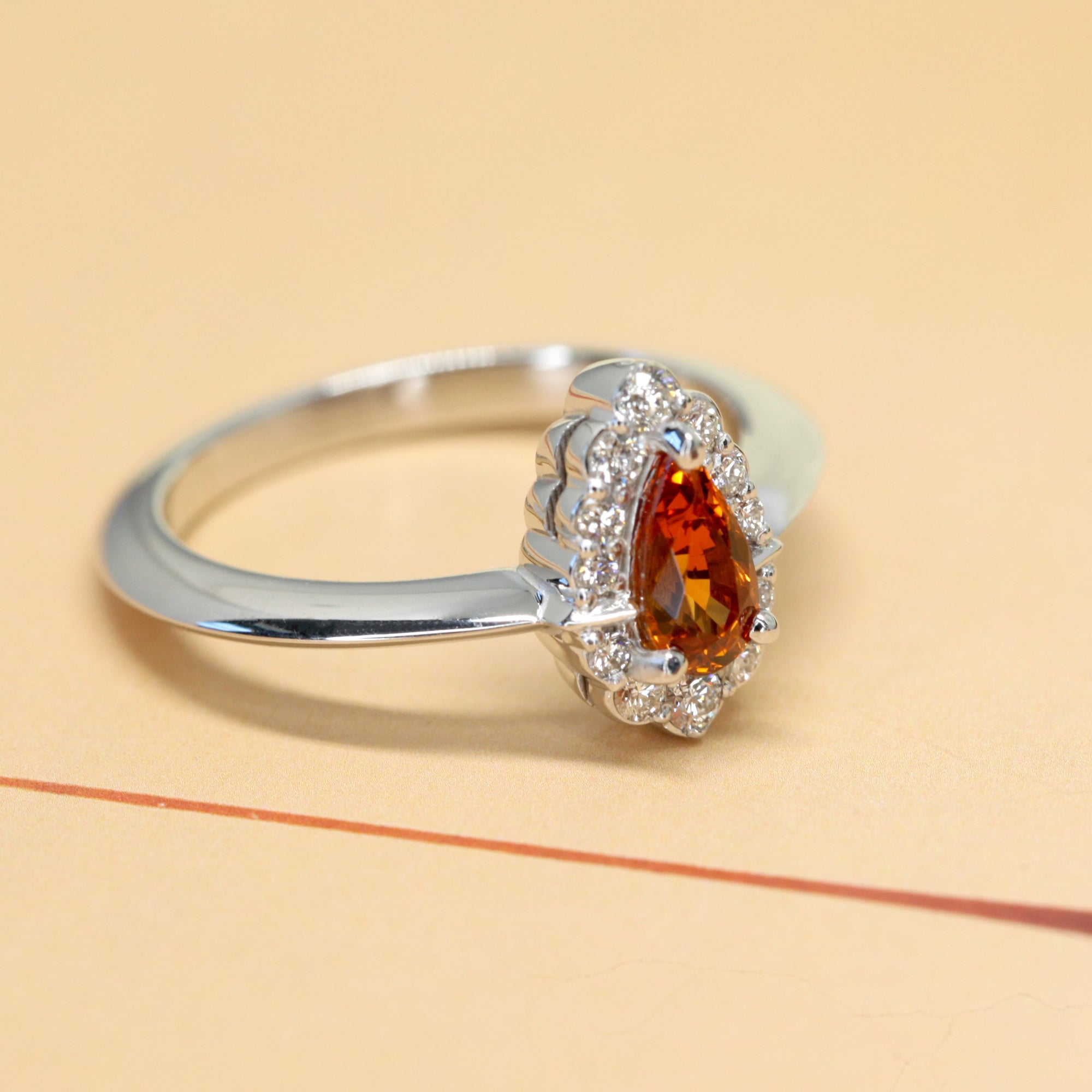 side view of white gold garnet and diamond engagement ring orange vivid spessartite garnet ring montreal bena jewelry handmade in little italy jeweler pear shape orange gemstone diamond ring color gems specialist montreal handmade fine jewelry