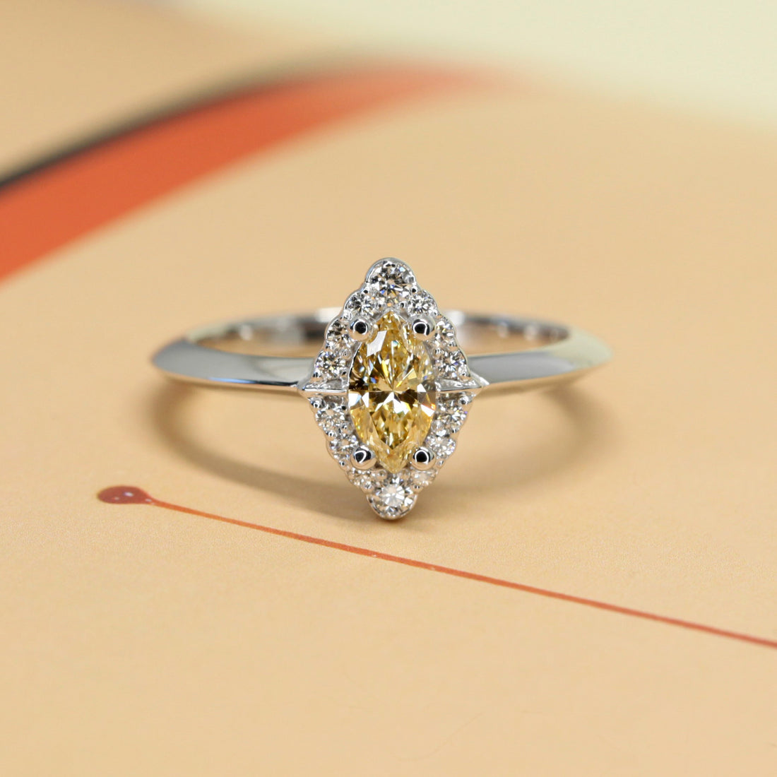 Bena jewelry ring on yellow background marquise shape natural color diamond ring bena jewelry montreal custom made bridal ring with white smal white round diamond fancy diamond halo design white gold ring bridal jewelry little italy jeweler