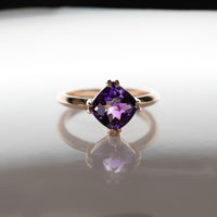 front view of amethyst rose gold ring deep purple high quality gemstone montreal on a grey background