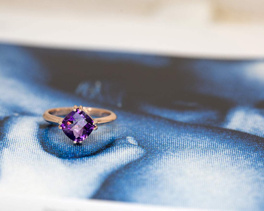 front view of cushion amethyst gemstone rose gold ring custom made in montreal by the bespoke jewellery designer bena jewelry montreal on a blue background